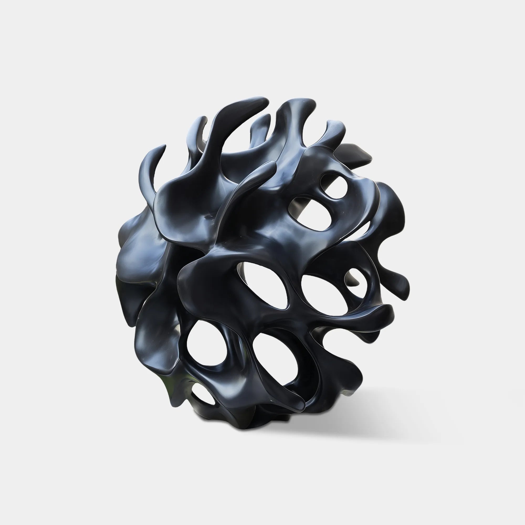 Matte black organic hollow abstract bronze sculpture in modern courtyard lawn