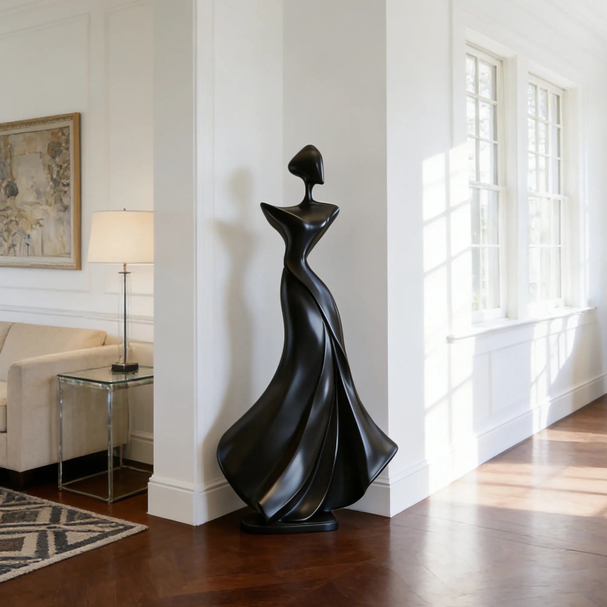 Black abstract bronze sculpture with flowing form in living room corner near white wall and window. 