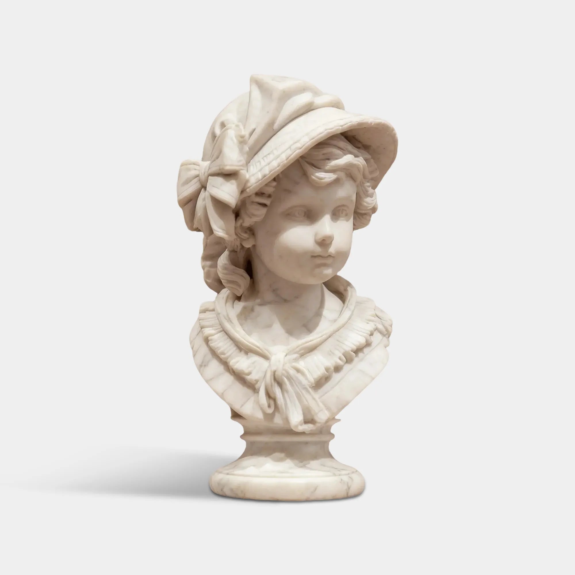 White marble little girl bust sculpture wearing a top hat on table.