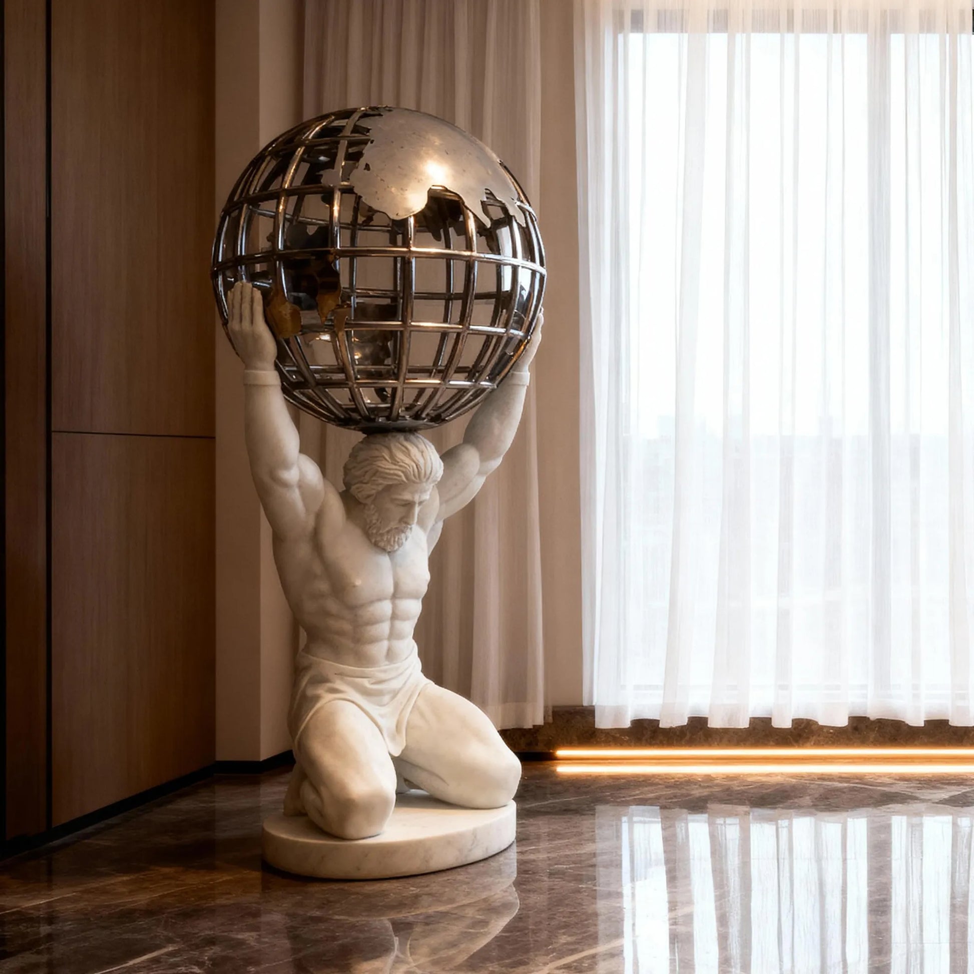 Decorative marble Atlas statue kneeling and holding a stainless steel sphere above his shoulders in front of a floor-to-ceiling window indoors.
