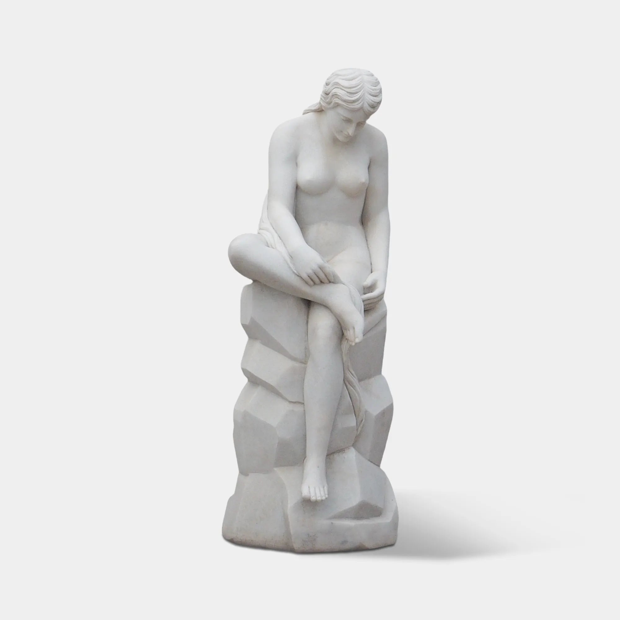 White marble seated female statue on stone base in front of classical columns and ivy-covered walls