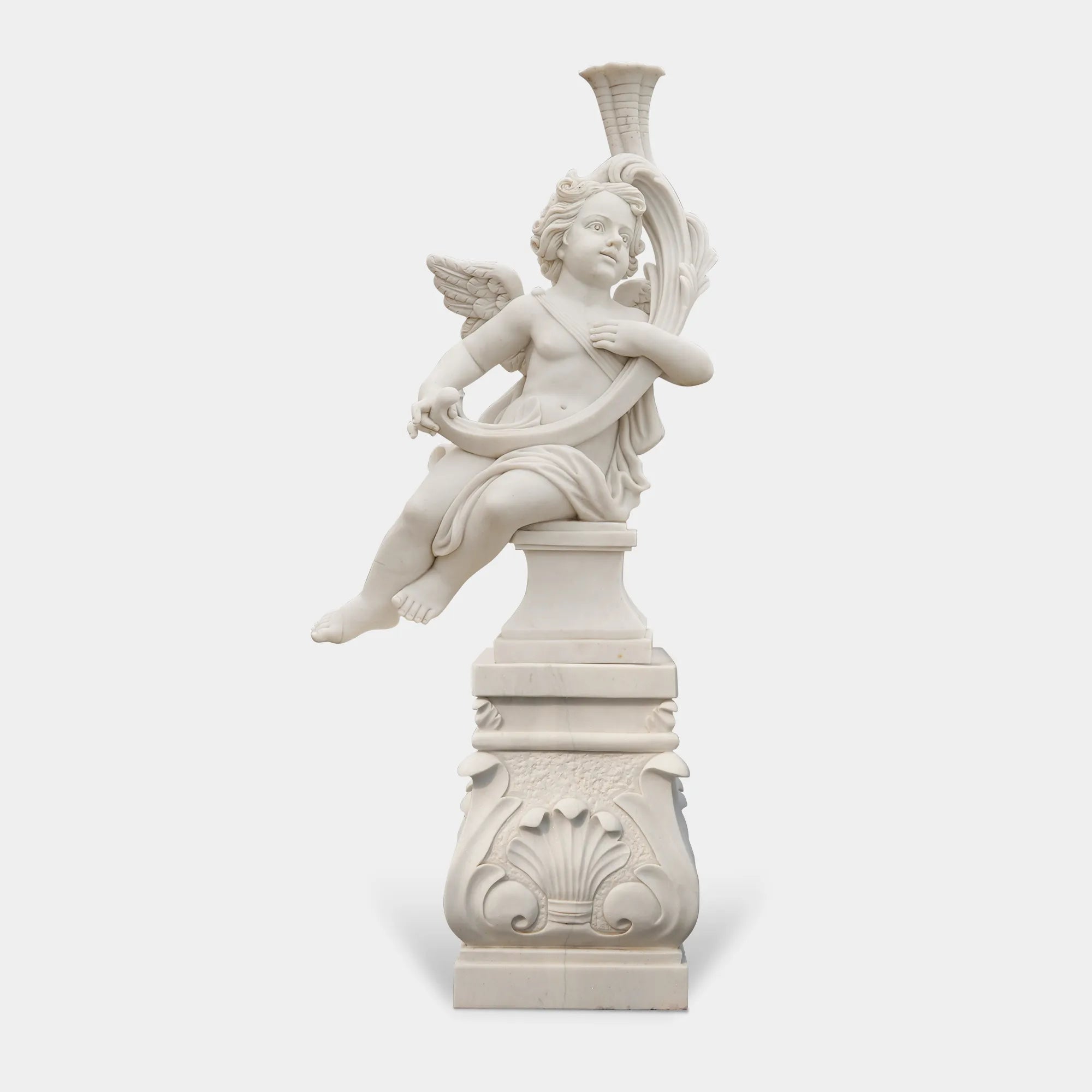 Cute cherub angel statue in white marble with wings sitting pose on base in a garden