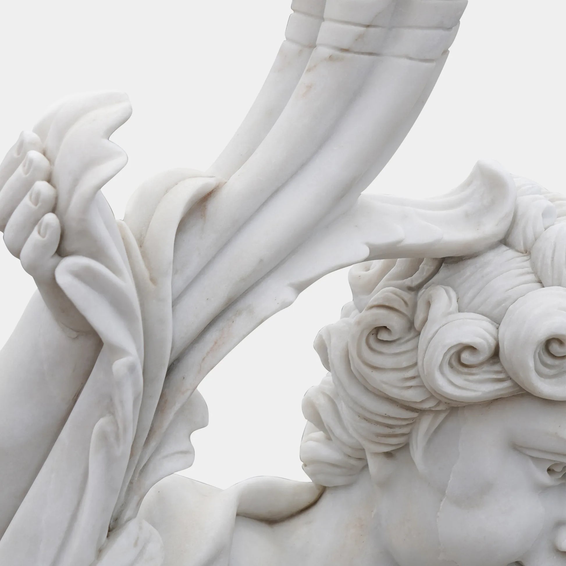 Cute cherub angel statue in white marble with wings sitting pose on base in a garden