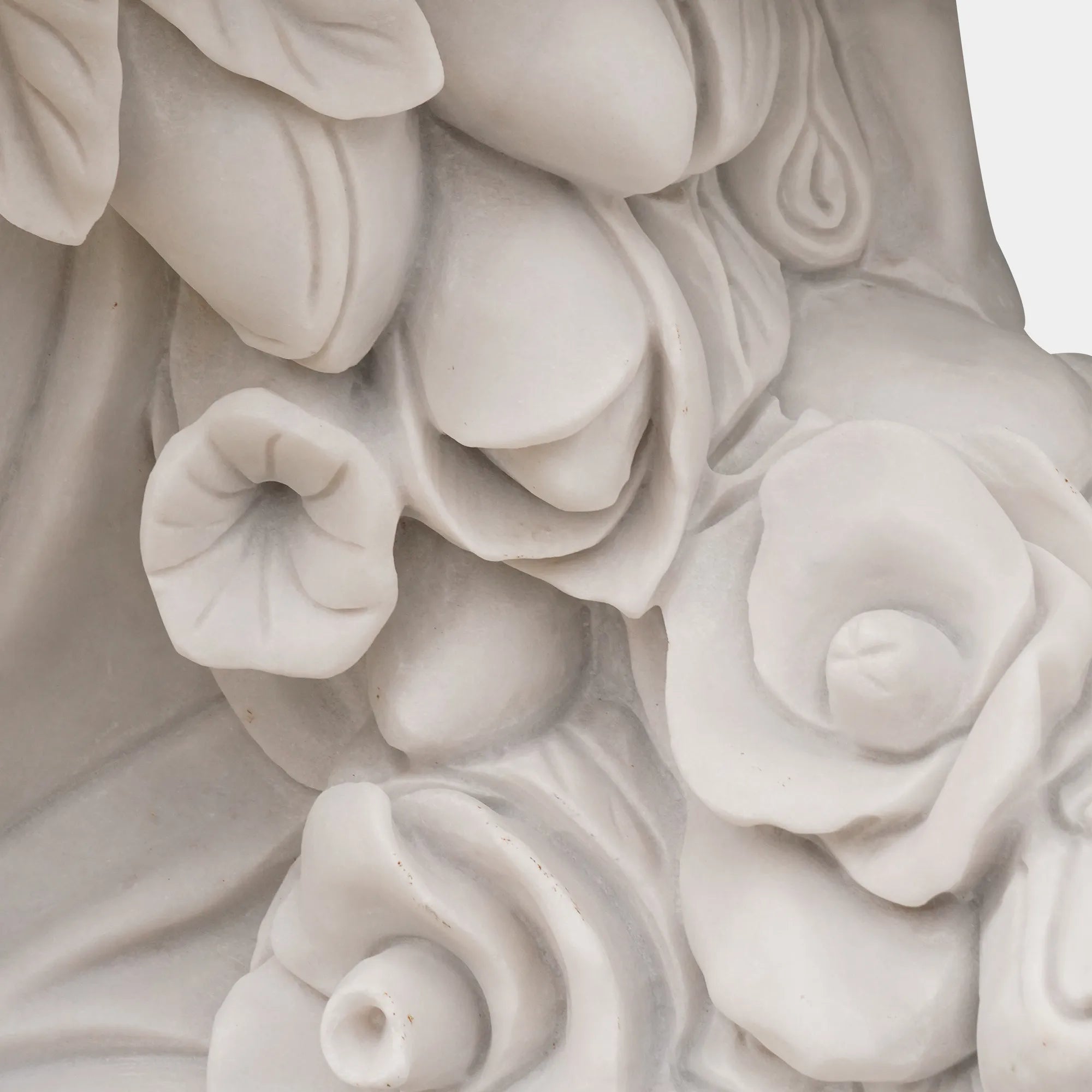 White marble statue of two female figures holding flowers in front of blooming rose garden with classical courtyard behind. 