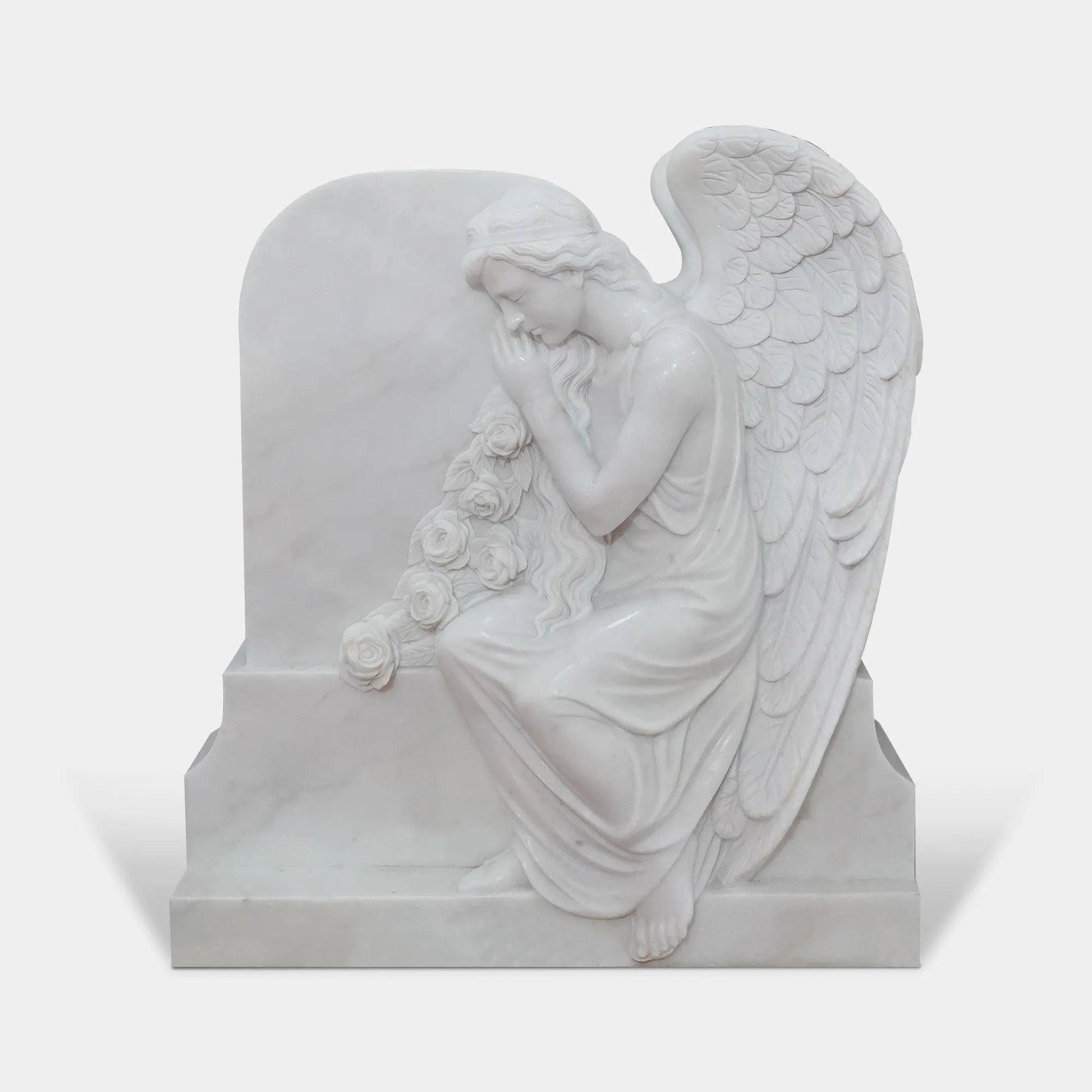 White marble angel statue leaning against a memorial marker in a cemetery garden, memorial setting