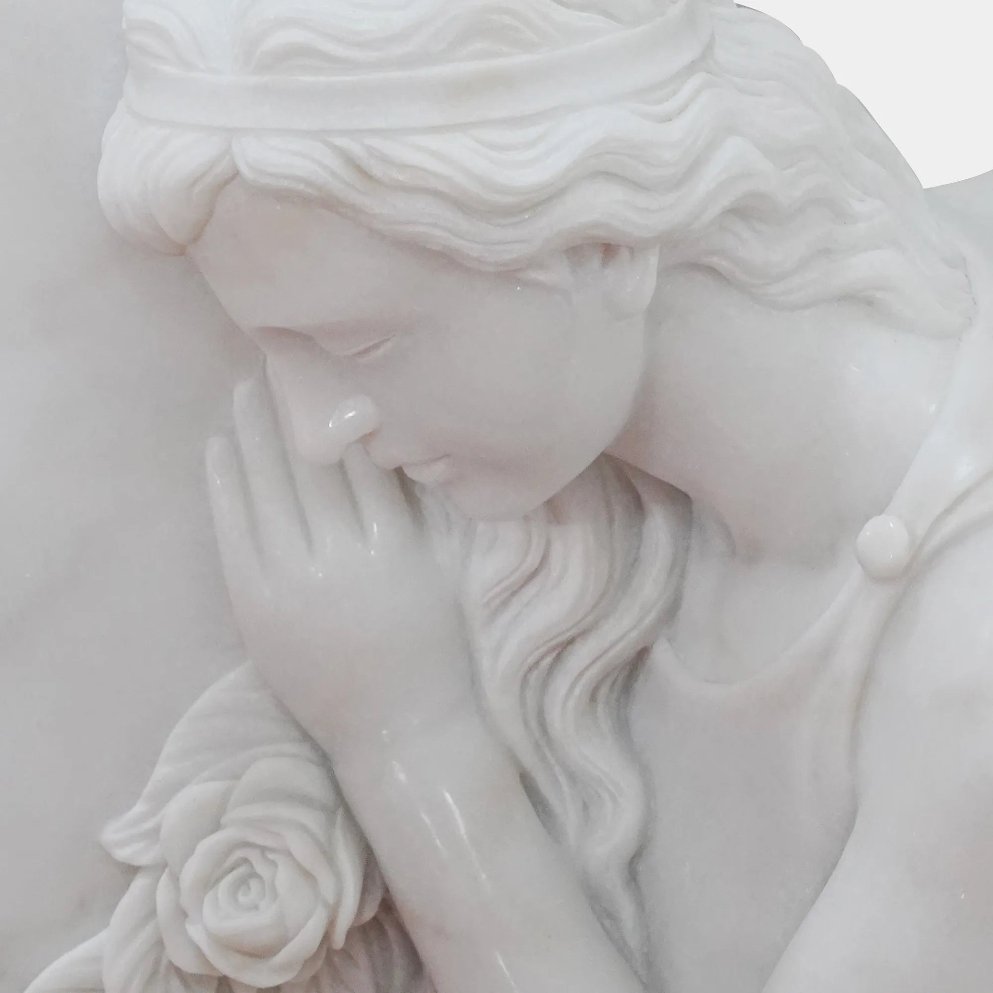 White marble angel statue leaning against a memorial marker in a cemetery garden, memorial setting