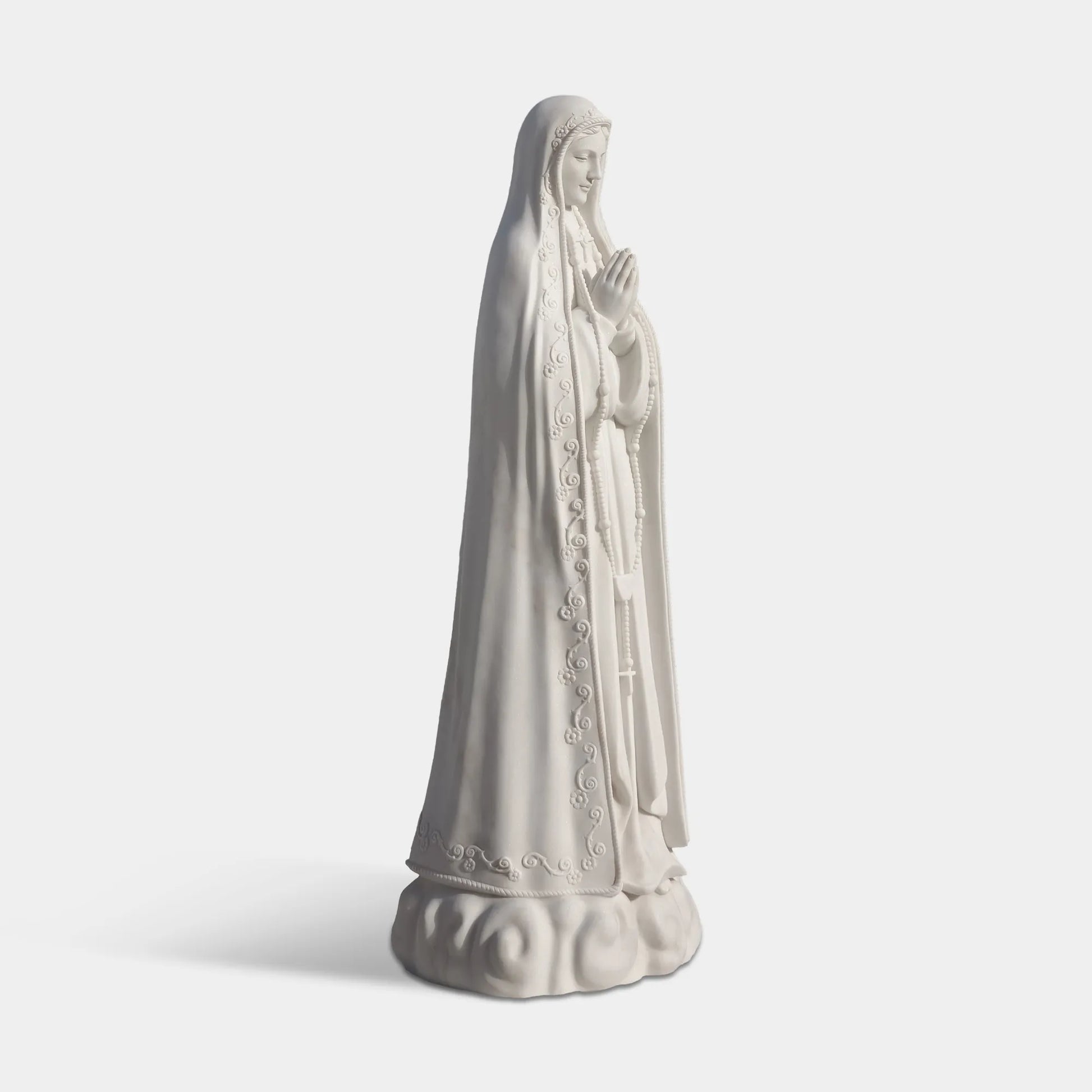 Our Lady of Fátima marble statue in front of a church with delicate carved details.