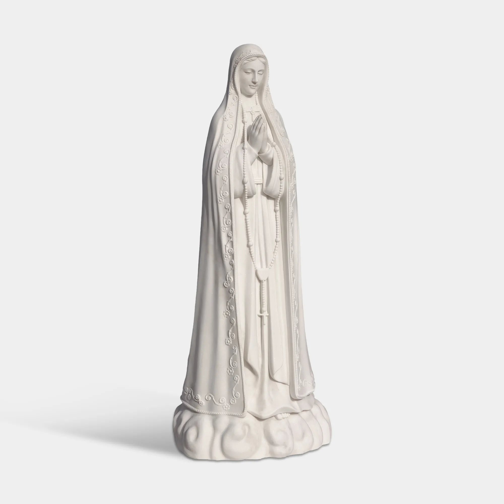 Our Lady of Fátima marble statue in front of a church with delicate carved details.