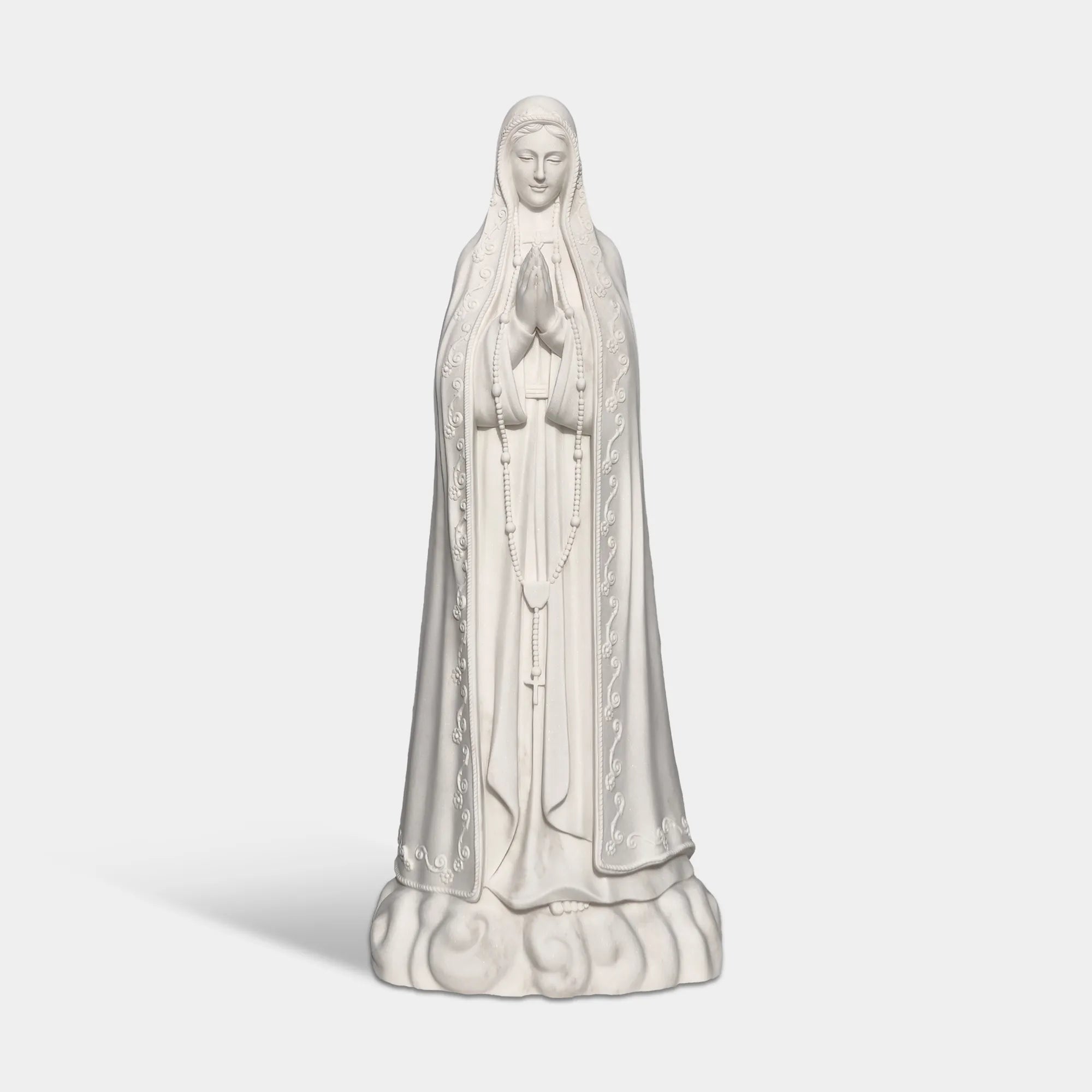 Our Lady of Fátima marble statue in front of a church with delicate carved details.