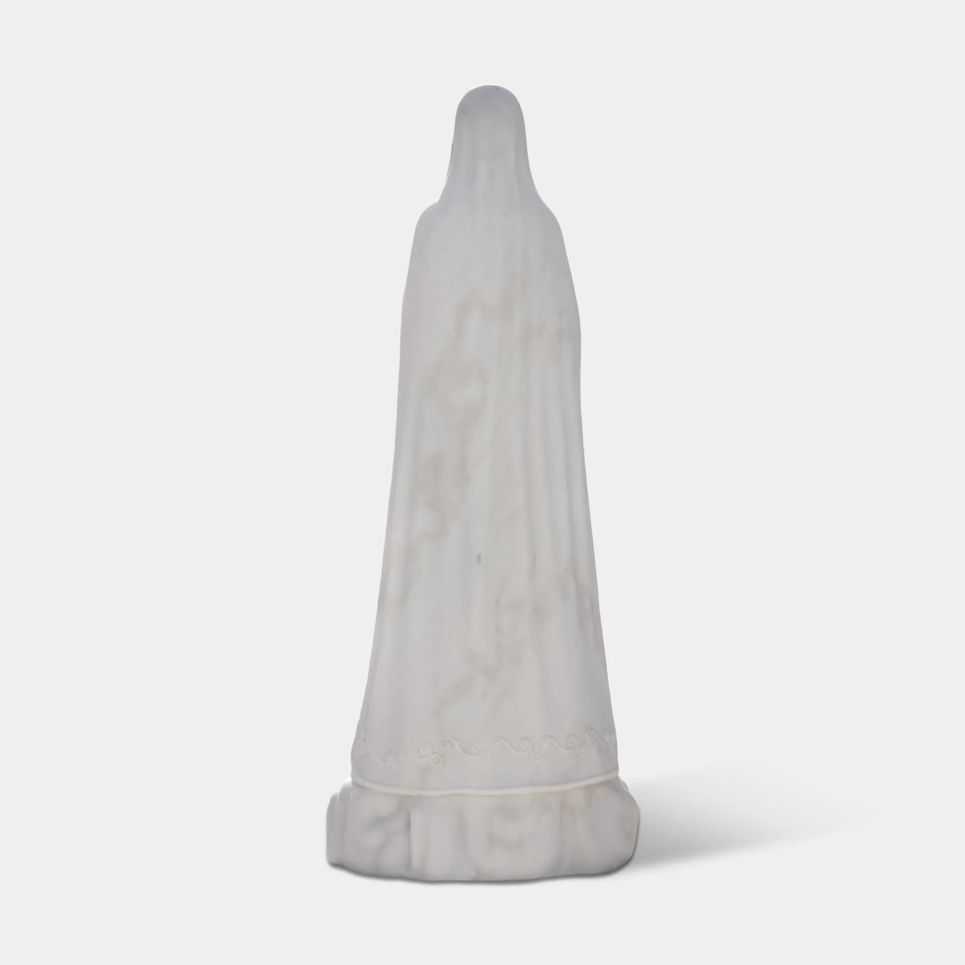 Our Lady of Fátima marble statue in front of a church with delicate carved details.