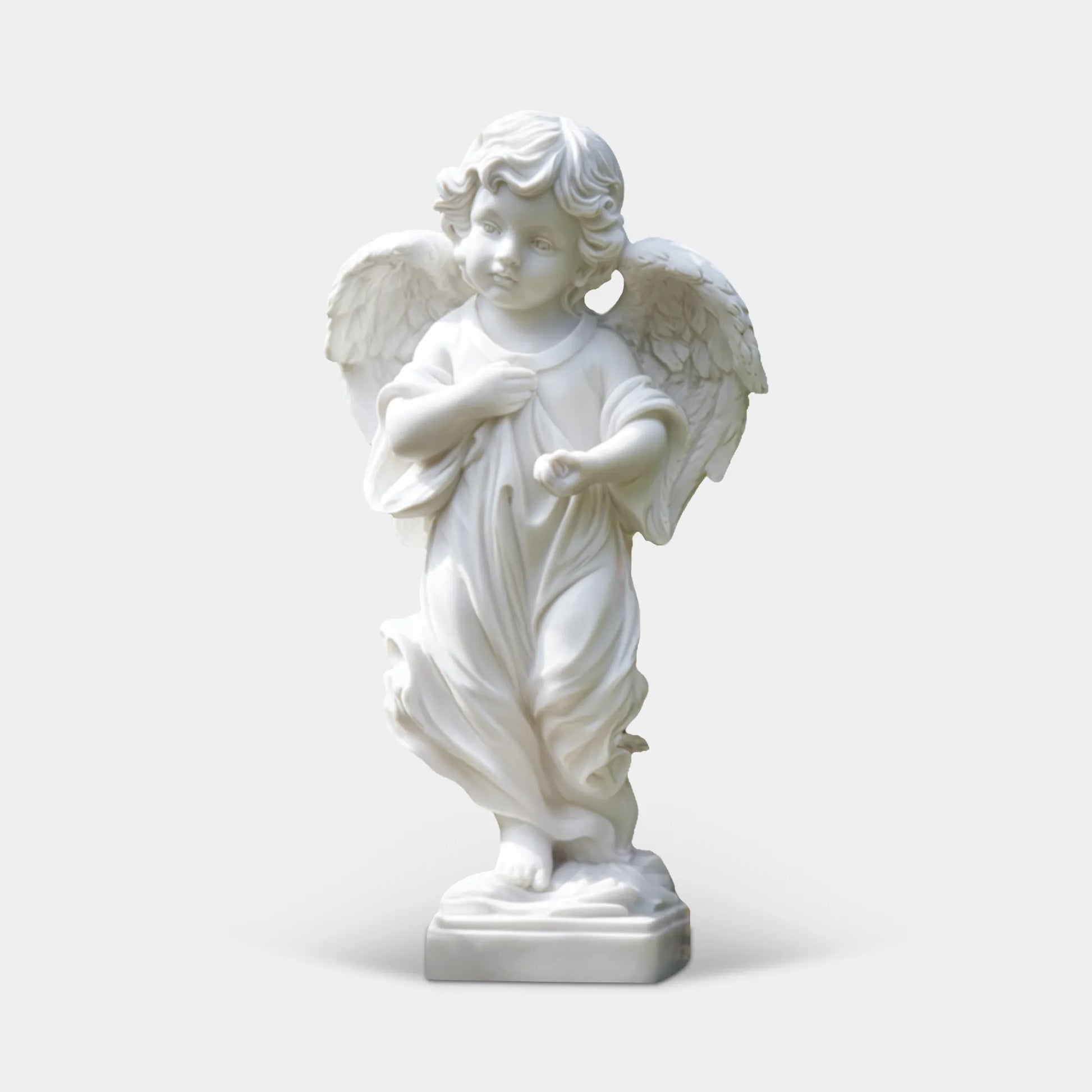 White marble angel statue with detailed wings and flowing robe in a formal garden pathway with trimmed hedges.