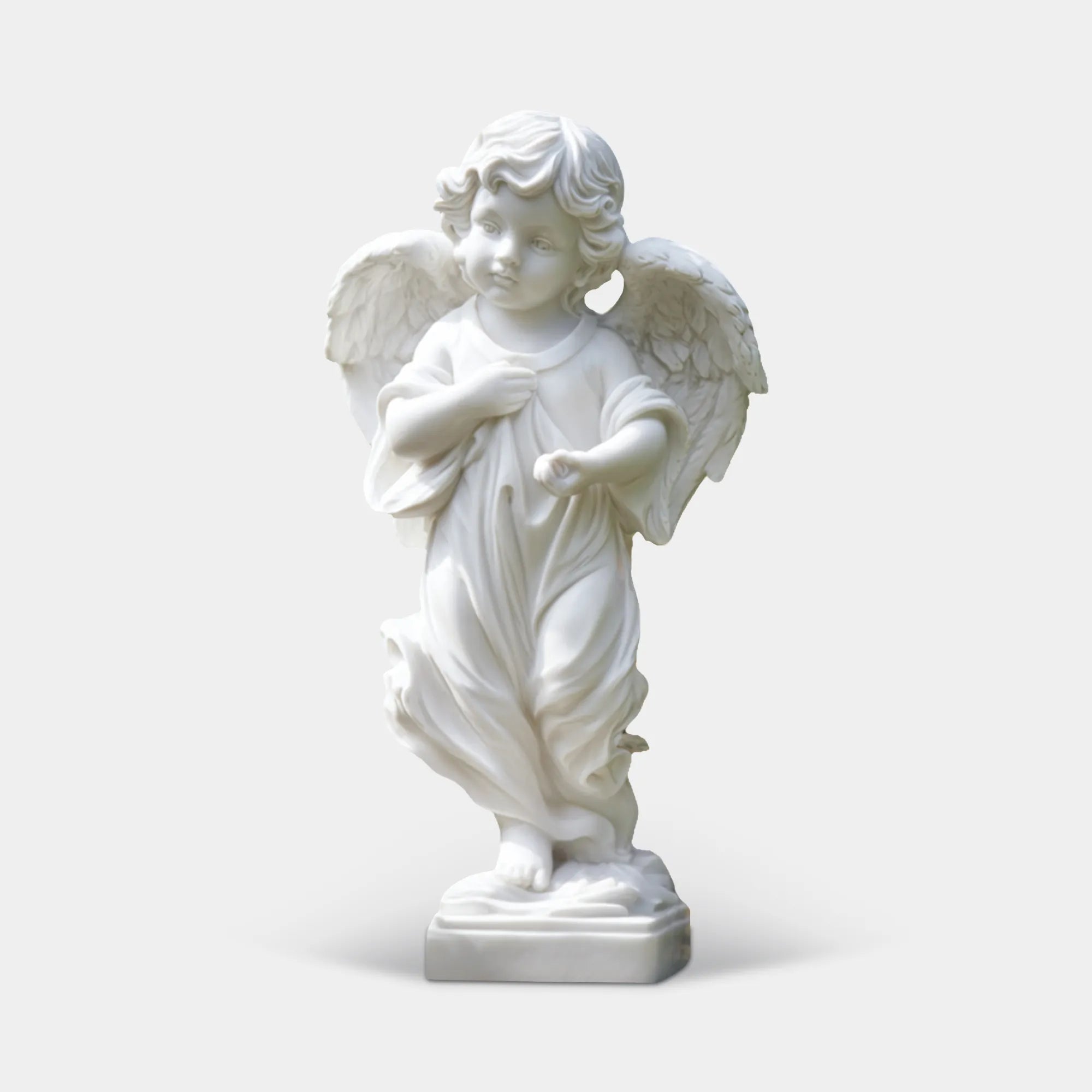 White marble angel statue with detailed wings and flowing robe in a formal garden pathway with trimmed hedges.