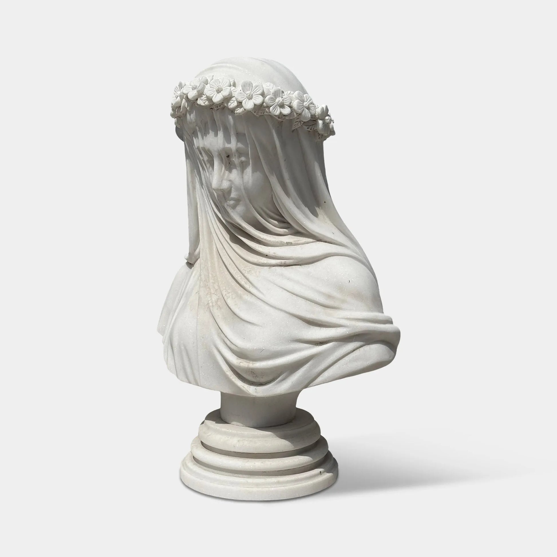 White marble veiled bust sculpture with flower crown in a luxury bedroom beside elegant classic furniture.