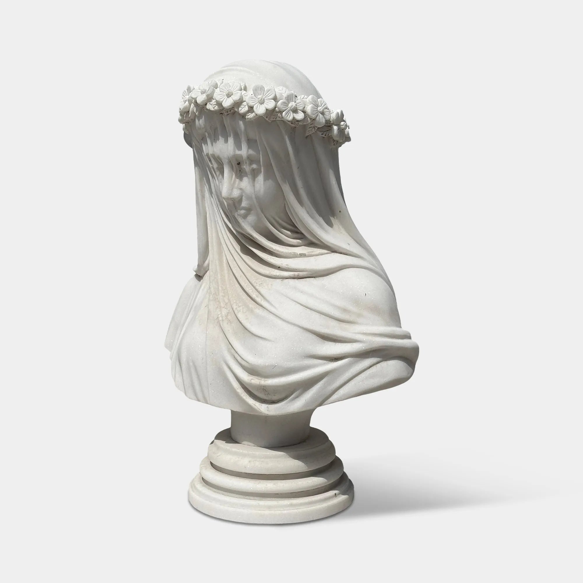 White marble veiled bust sculpture with flower crown in a luxury bedroom beside elegant classic furniture.
