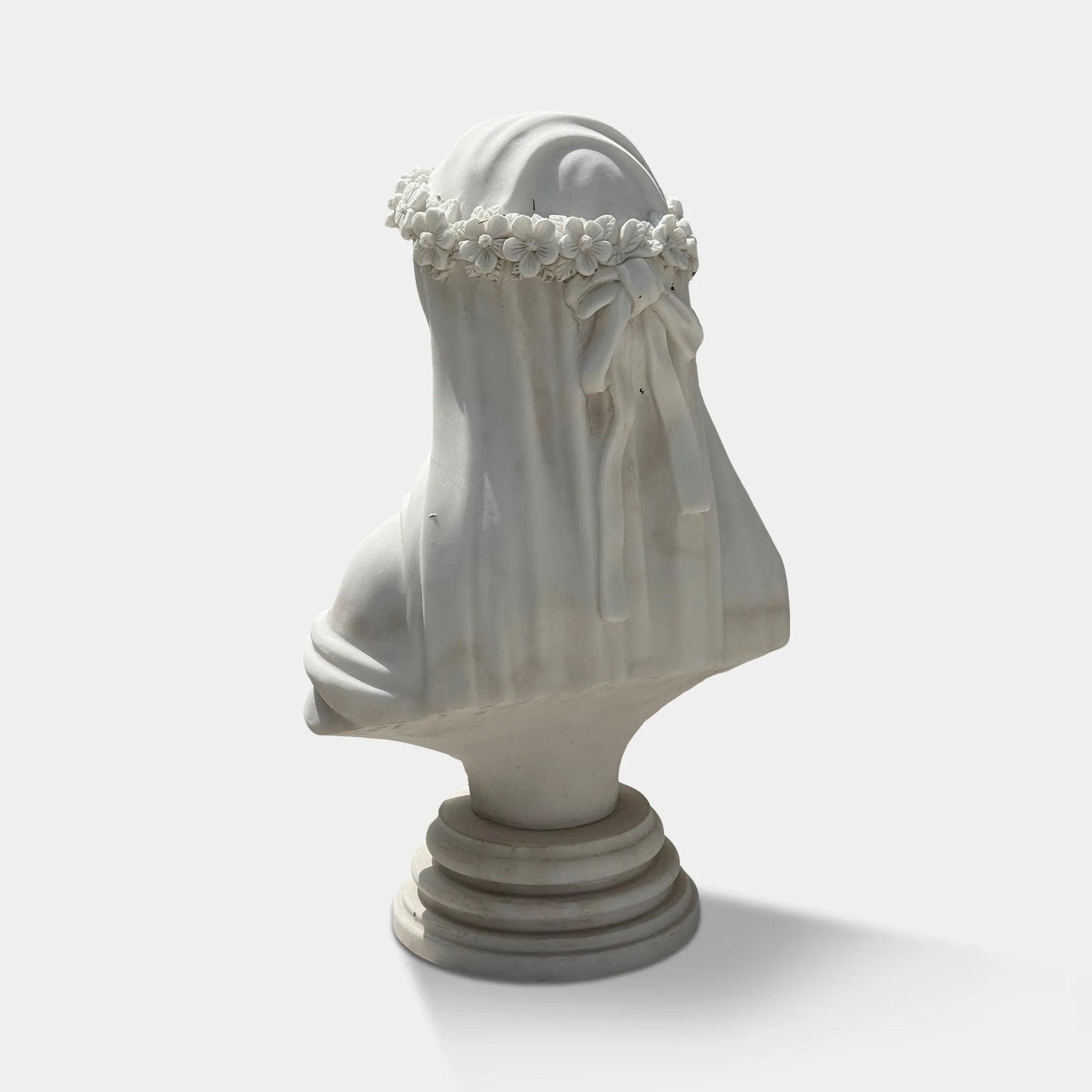 White marble veiled bust sculpture with flower crown in a luxury bedroom beside elegant classic furniture.