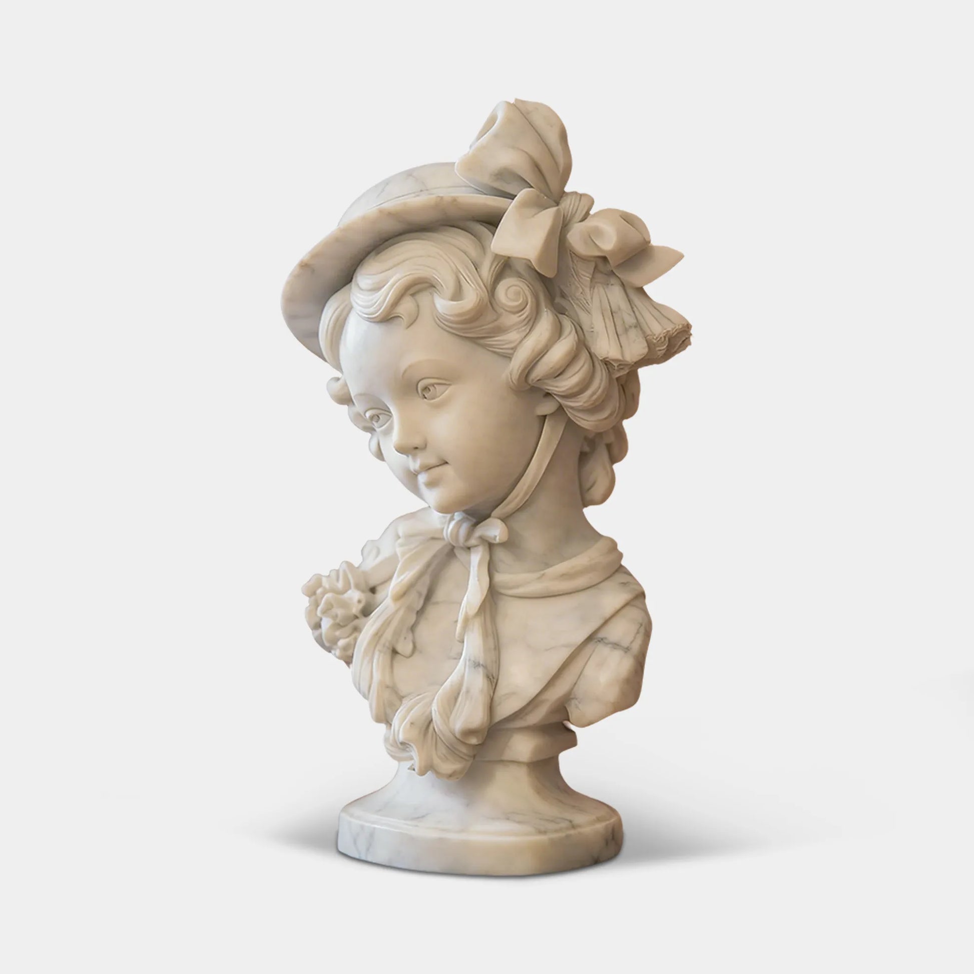White marble classic girl bust sits on marble table in front of gilded antique mural.