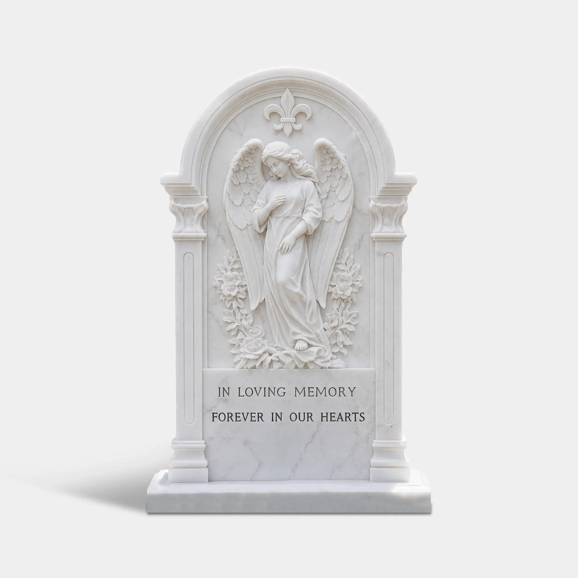 White marble tombstone with angel relief at top and circular wreath carving below in cemetery garden.