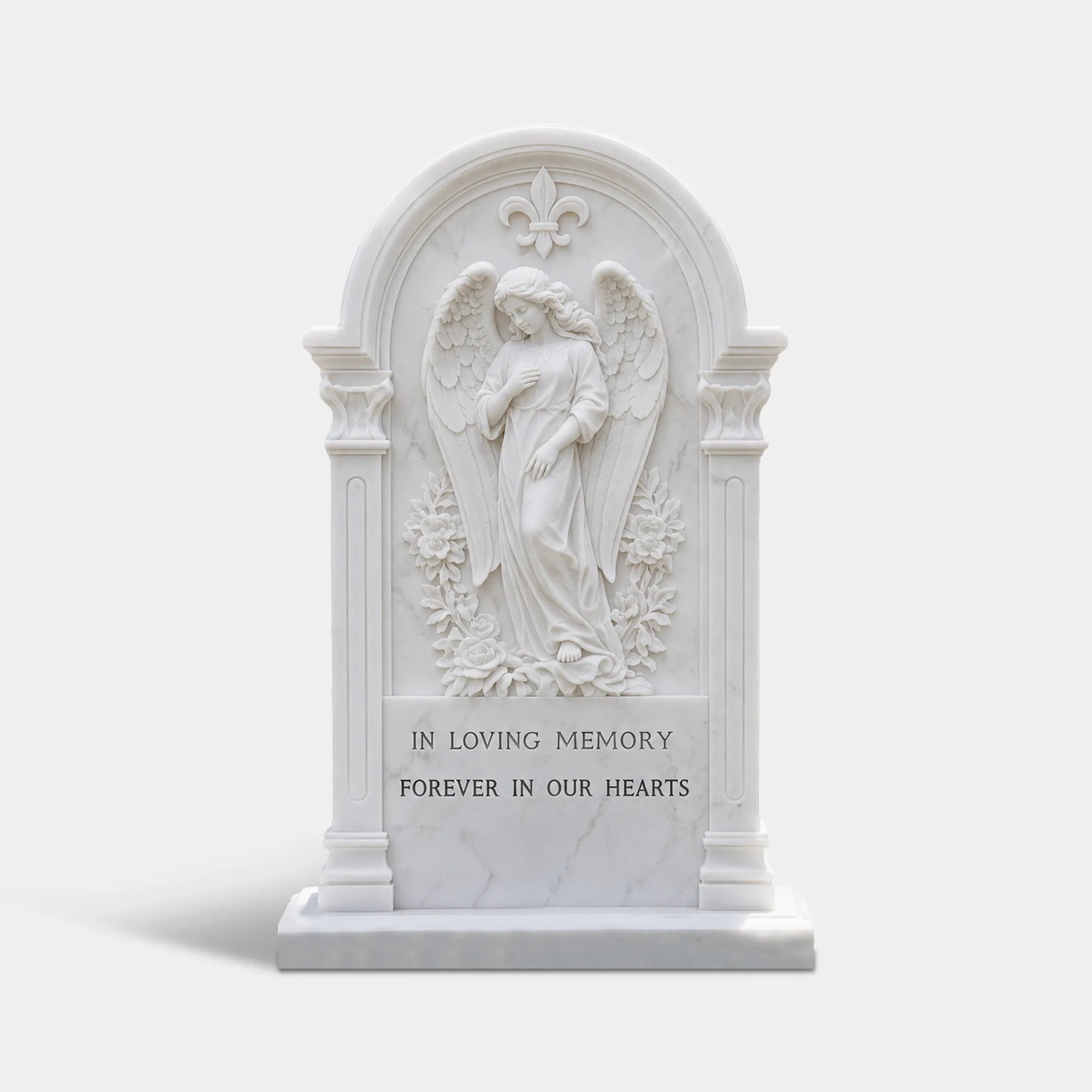 White marble tombstone with angel relief at top and circular wreath carving below in cemetery garden.