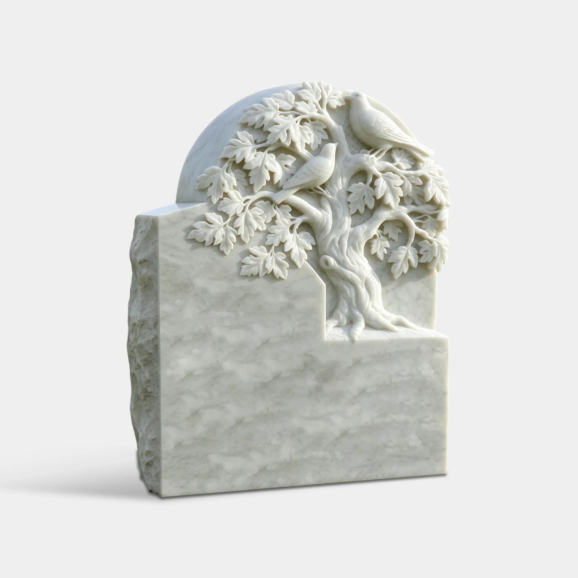 White marble headstone carved with tree and two dove sits on a green cemetery lawns.