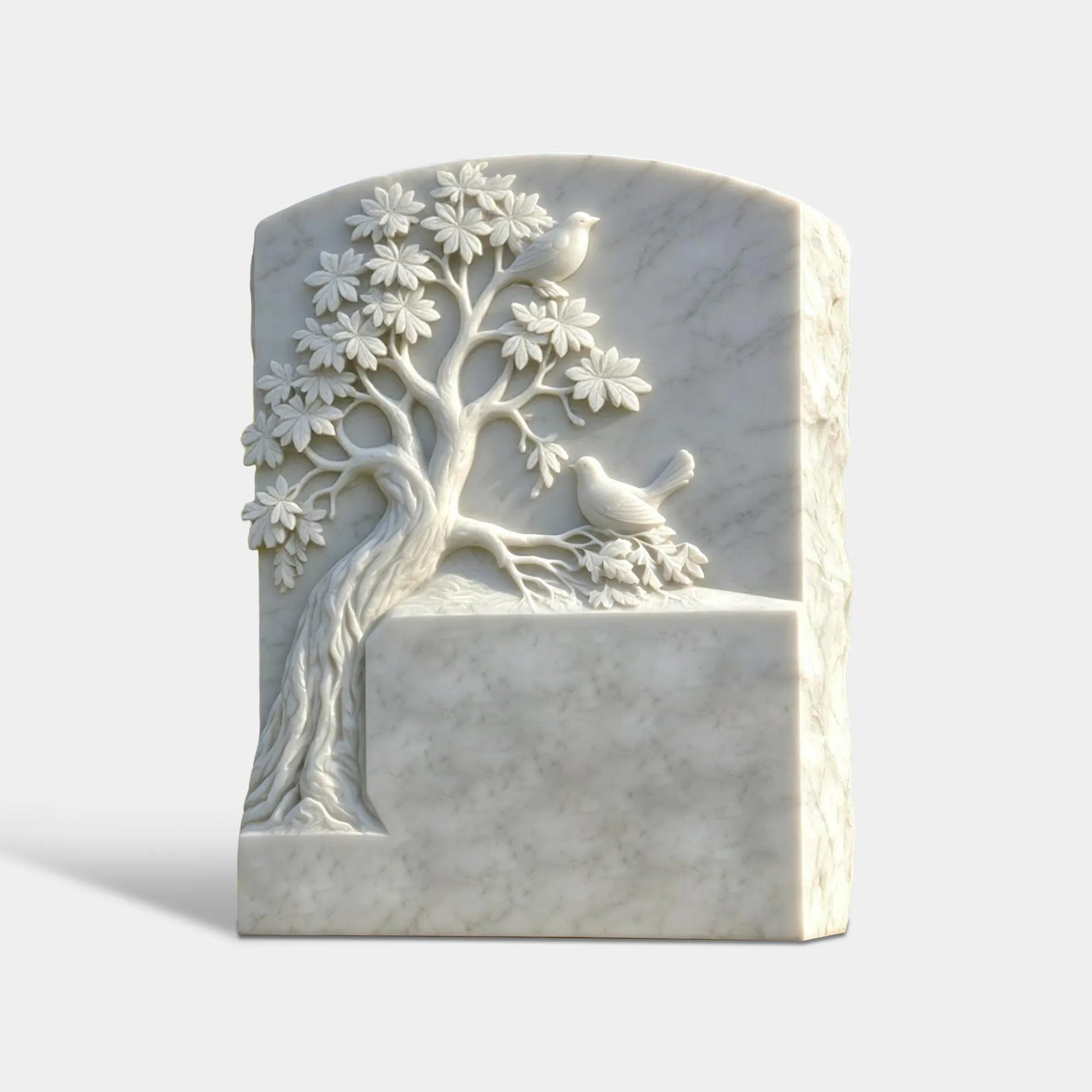 Curved white marble tombstone carved tree and two birds on a grassy cemetery.