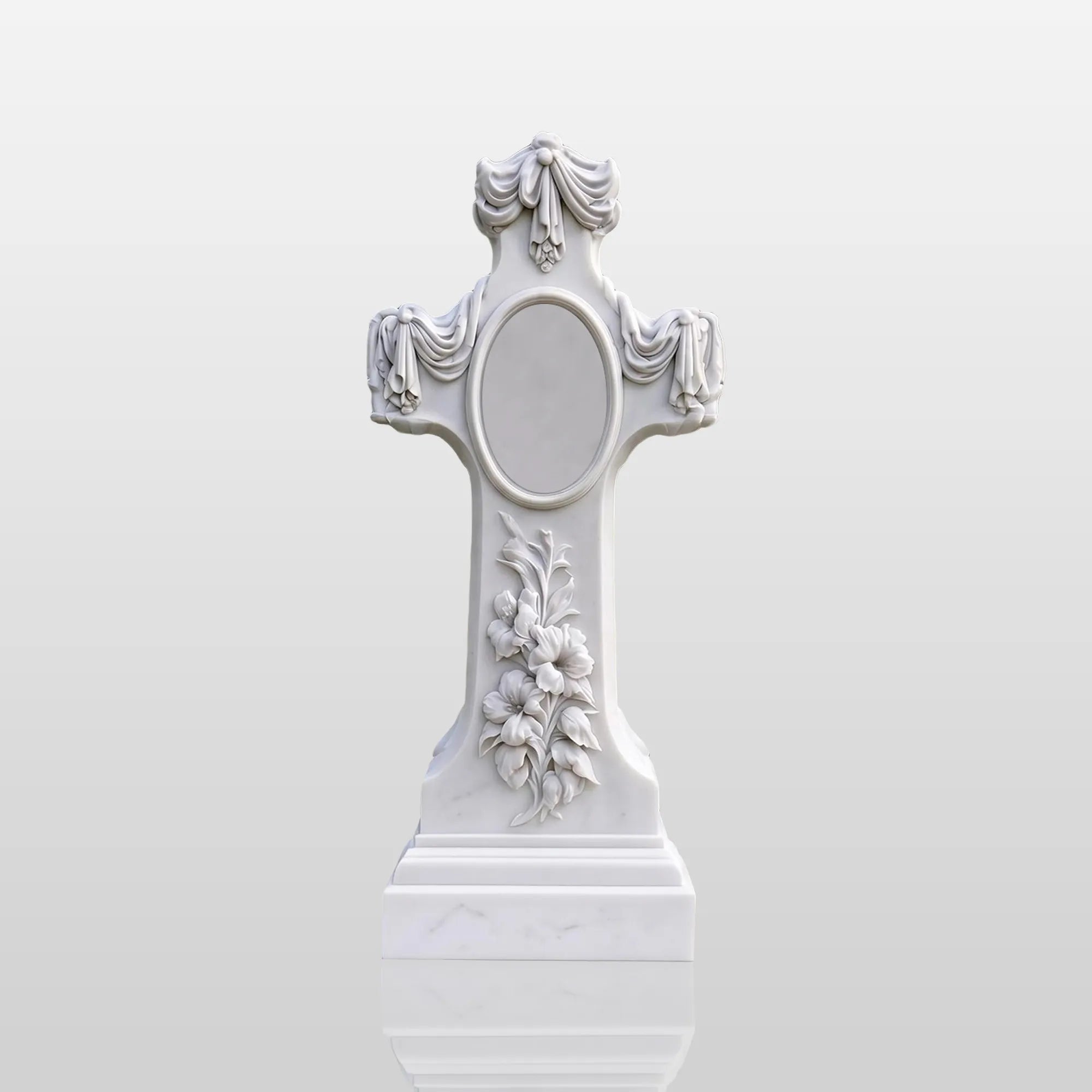 White marble memorial cross statue with floral relief carving and draped fabric details in cemetery memorial garden.