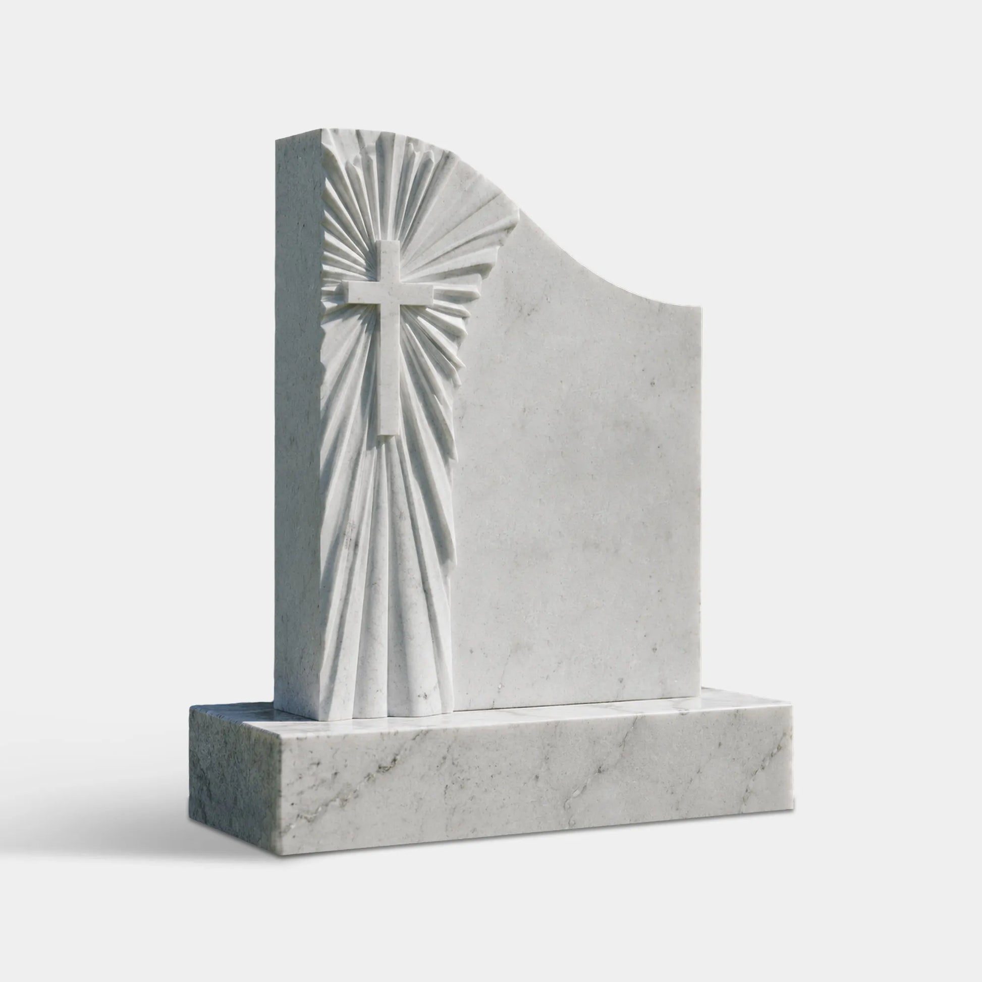White marble Christian headstone with a carved cross and radiating sunburst on a rectangular base in a cemetery lawn.