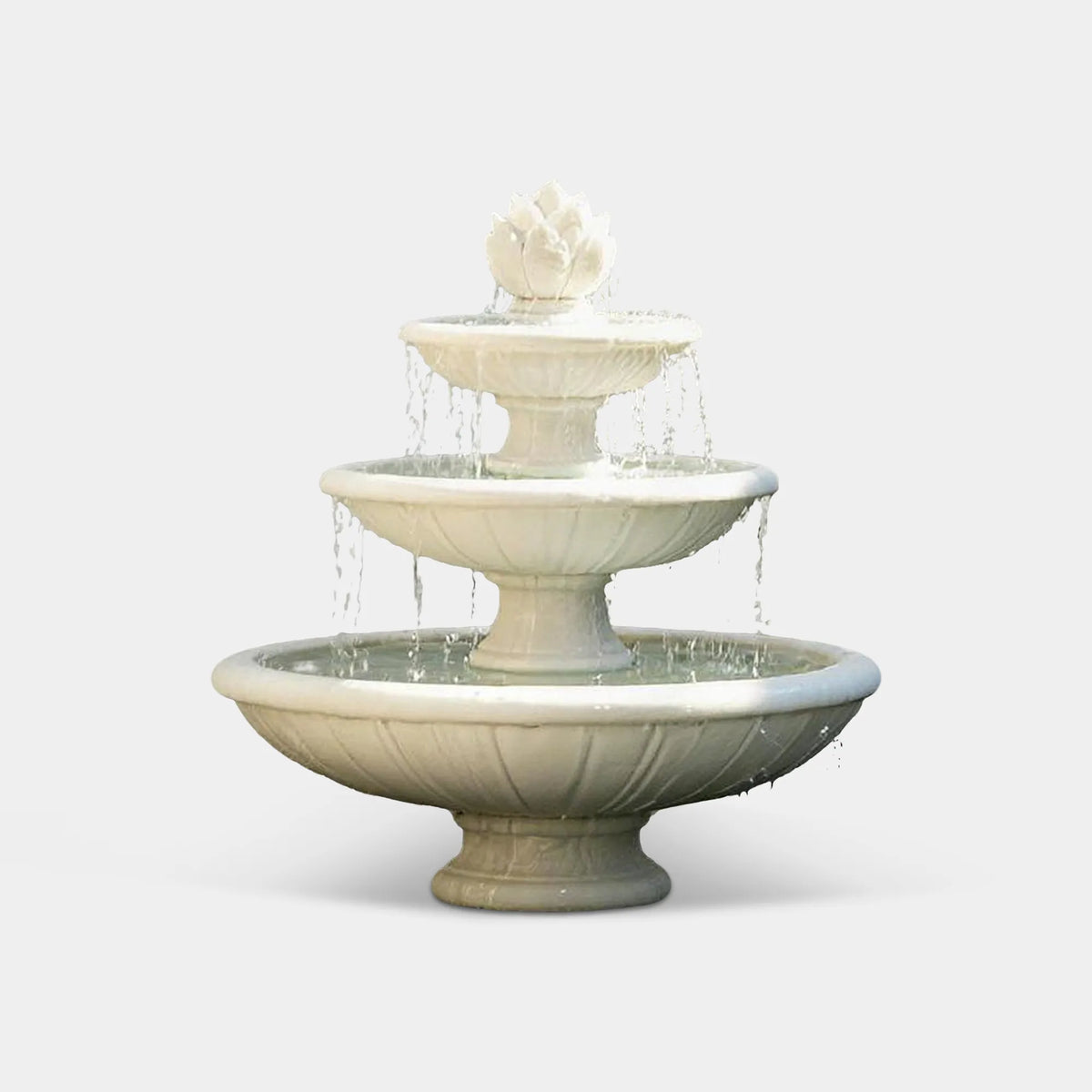 A three tier white marble fountain with lotus detail sits in a wall side outdoor patio space.