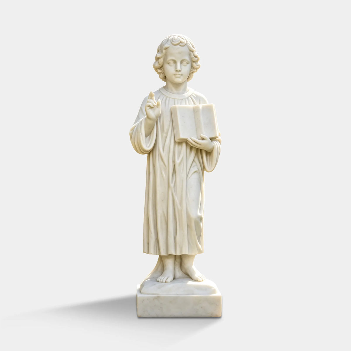 A white marble statue of young Jesus stands in a trimmed green circular shrub bed inside a courtyard.