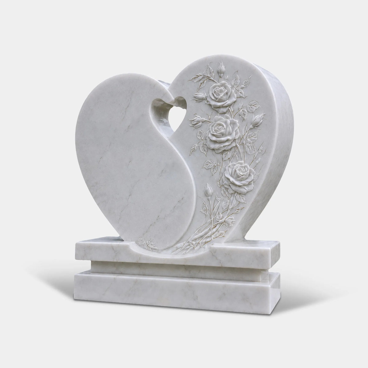 A white marble heart headstone with rose carvings stands in a cemetery.