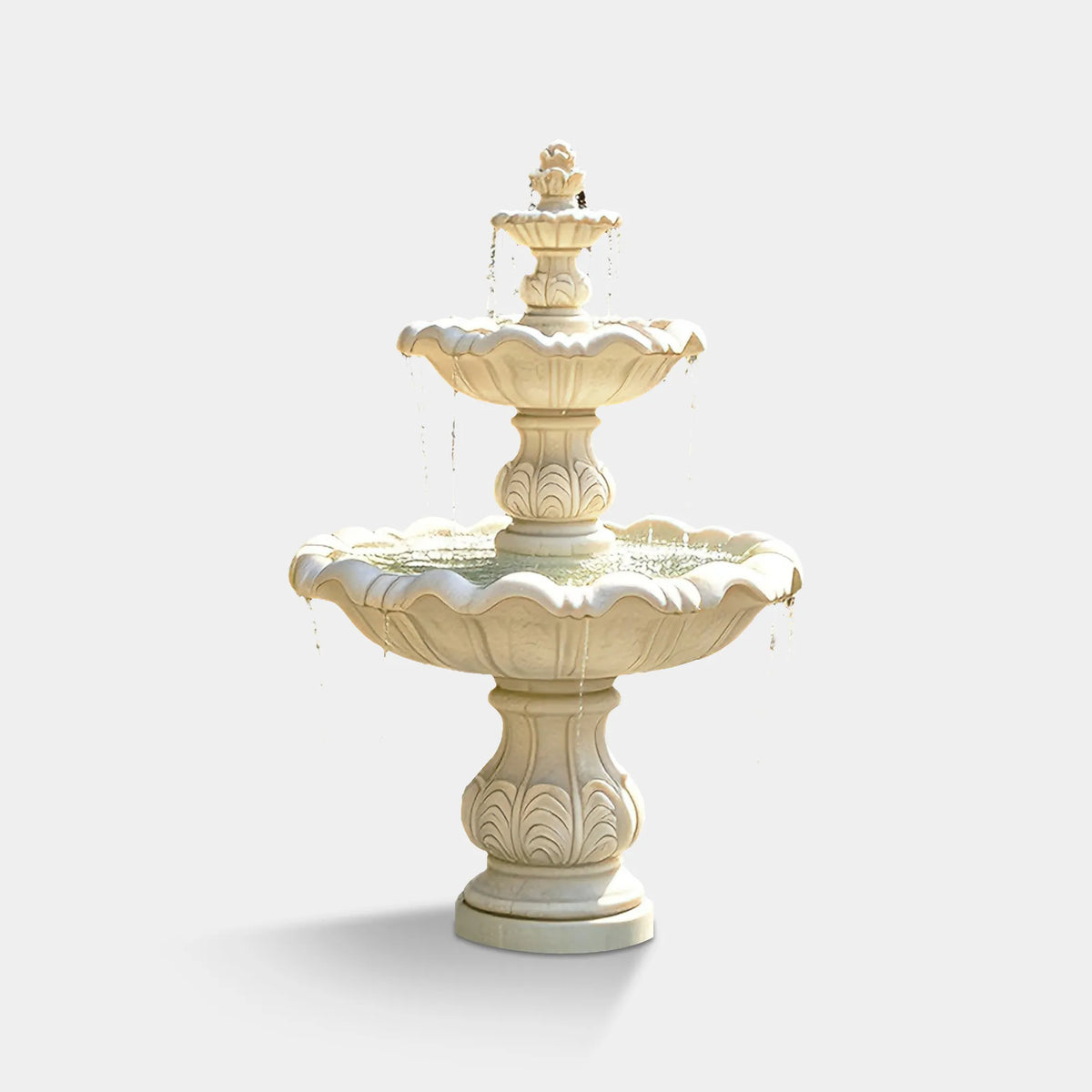 White marble fountain with scalloped basins in a backyard garden with flowers and patio seating.