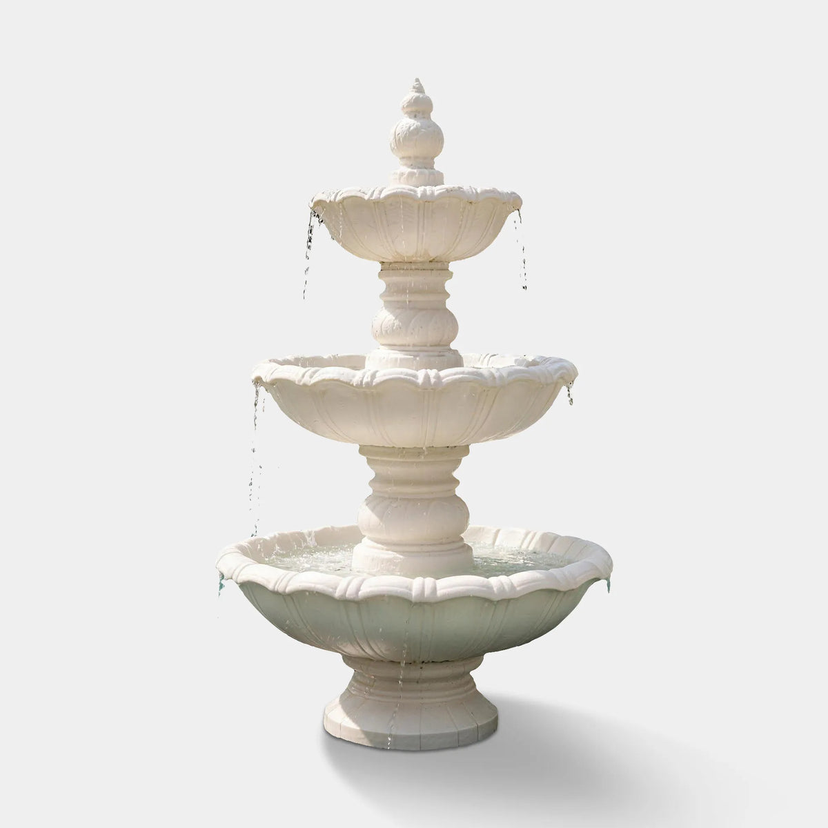 A white three tier marble fountain stands in a tropical villa backyard.