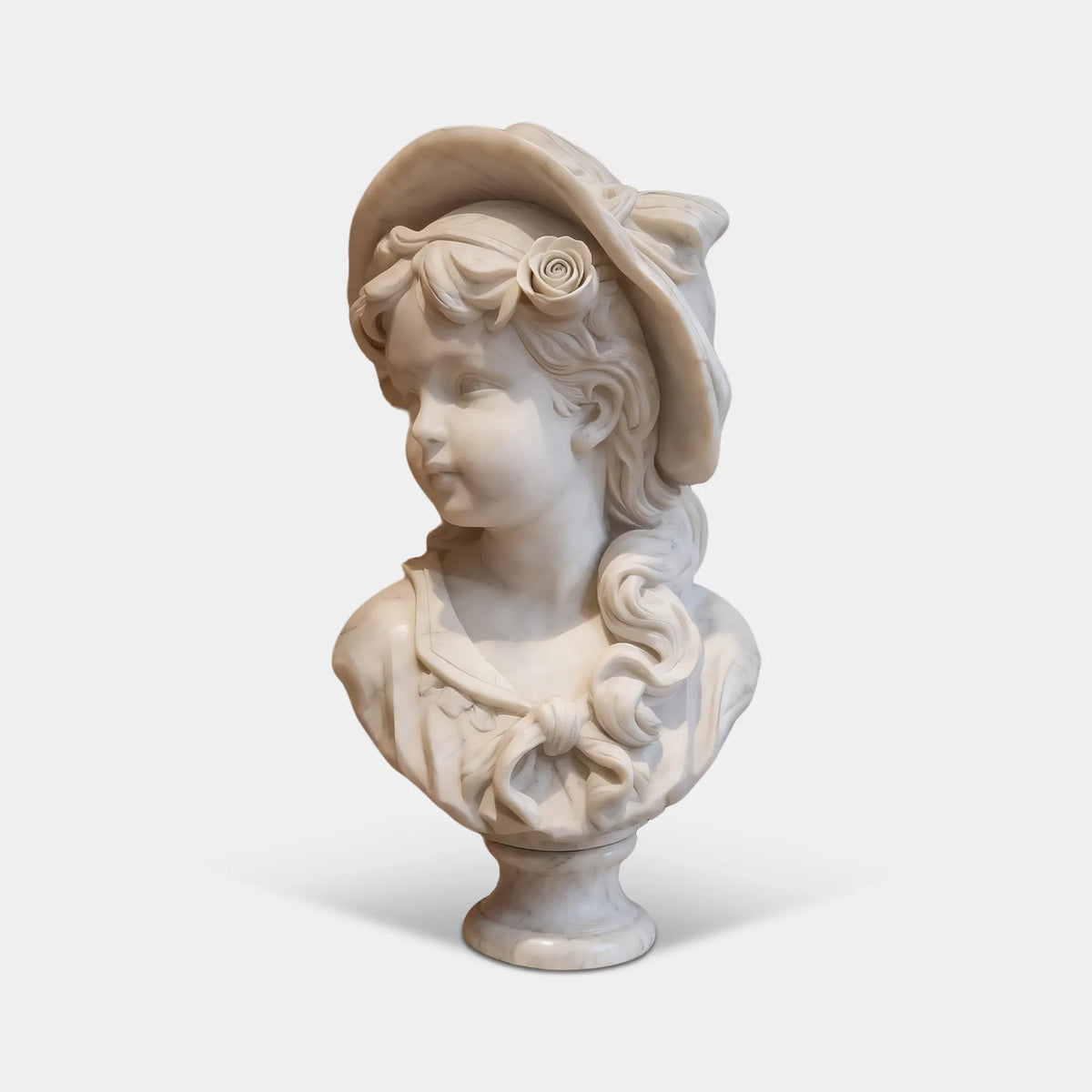 White marble girl bust sculpture featuring a floral hat, softly curled hair, and detailed clothing on a rounded pedestal in an elegant French-style living room.