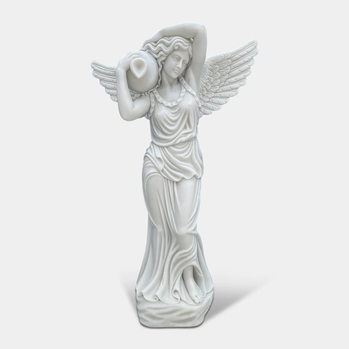 A white marble goddess statue with wings and water jug sits in a pool within a garden.