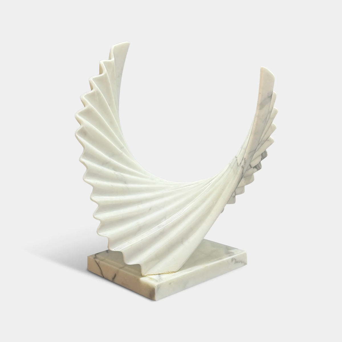 A marble wings sculpture sits on a dark marble console table in a warm living room.