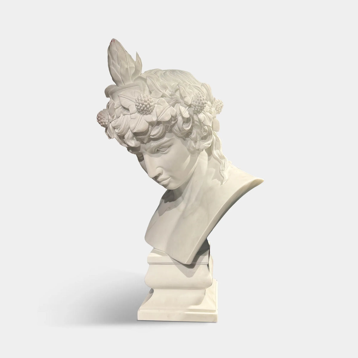 A marble Antinous bust sits on a speckled round stone table inside a warm room.