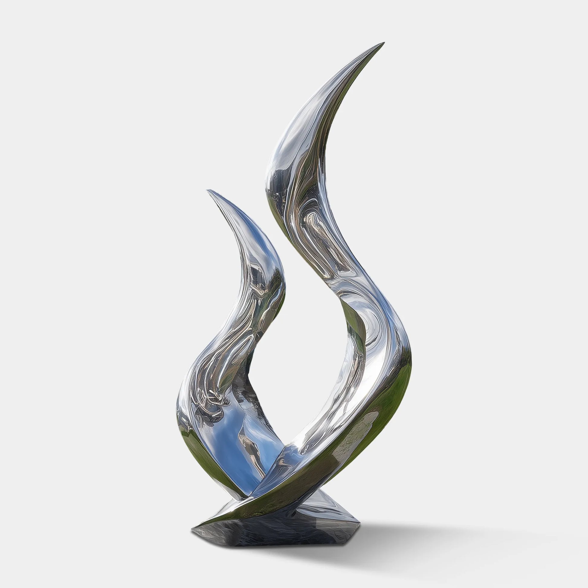 Polished stainless steel flowing abstract sculpture on stone base in green lawn in front of modern villa