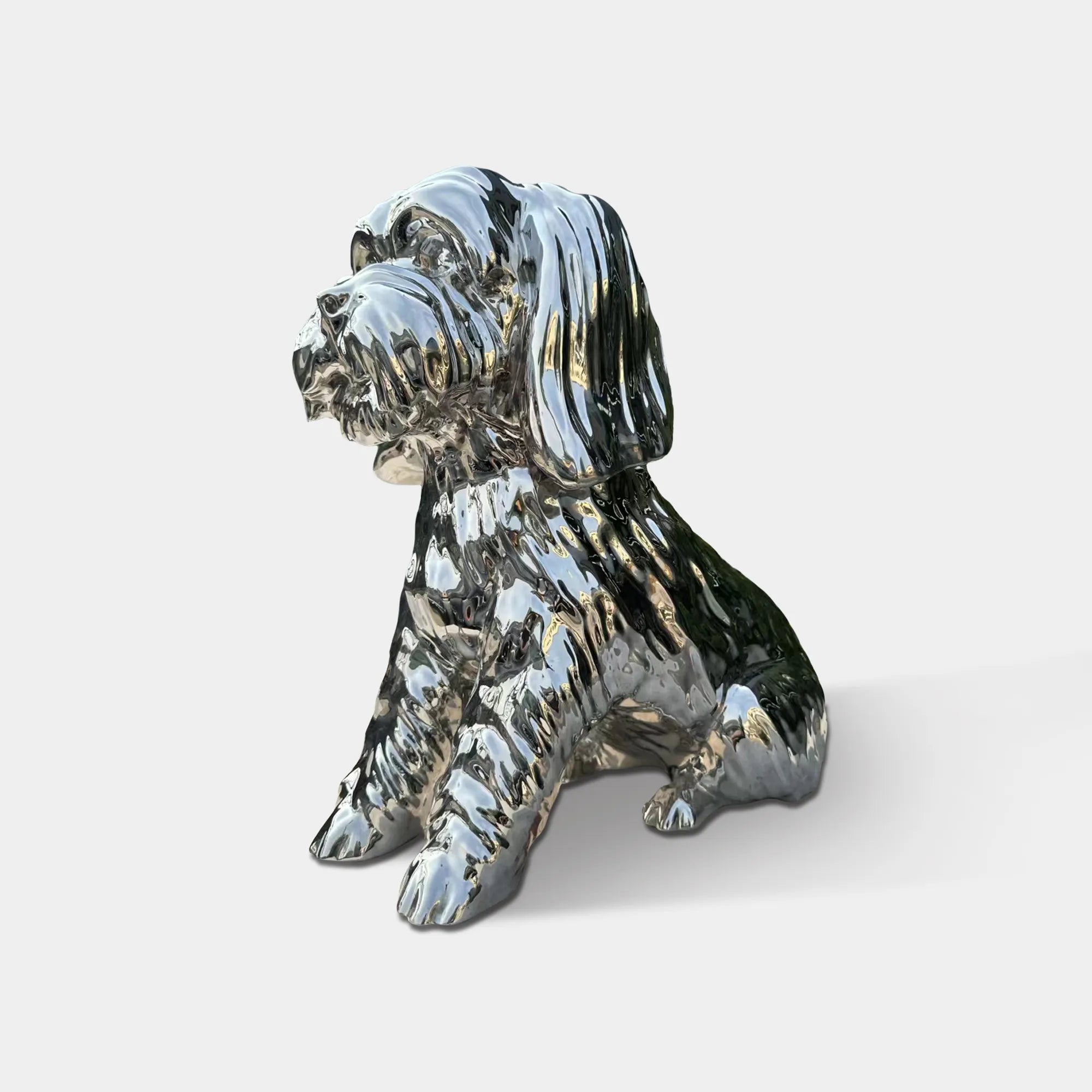 Polished stainless steel seated dog sculpture with reflective surface and detailed fur texture in modern interior with wood wall panels and marble floor