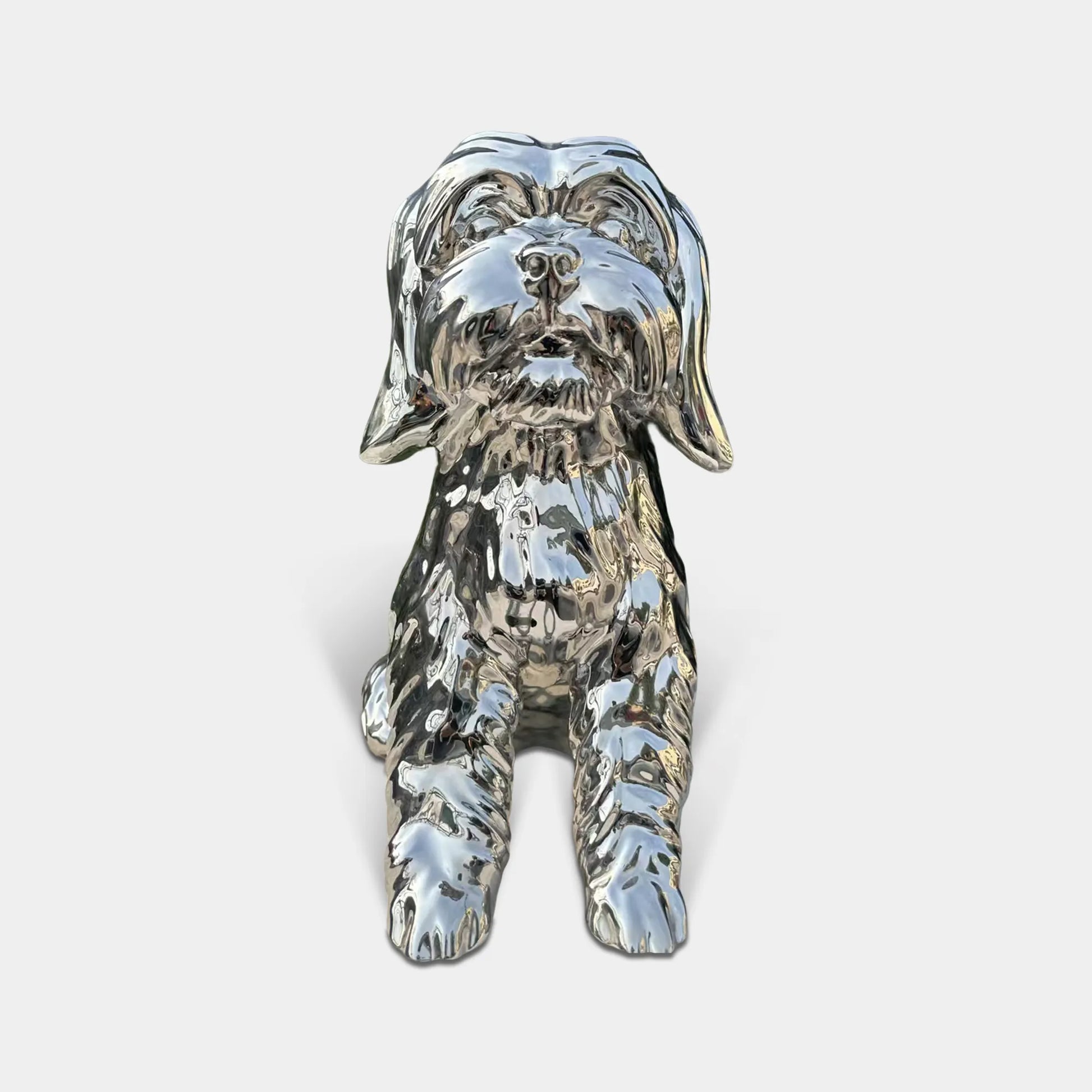 Polished stainless steel seated dog sculpture with reflective surface and detailed fur texture in modern interior with wood wall panels and marble floor