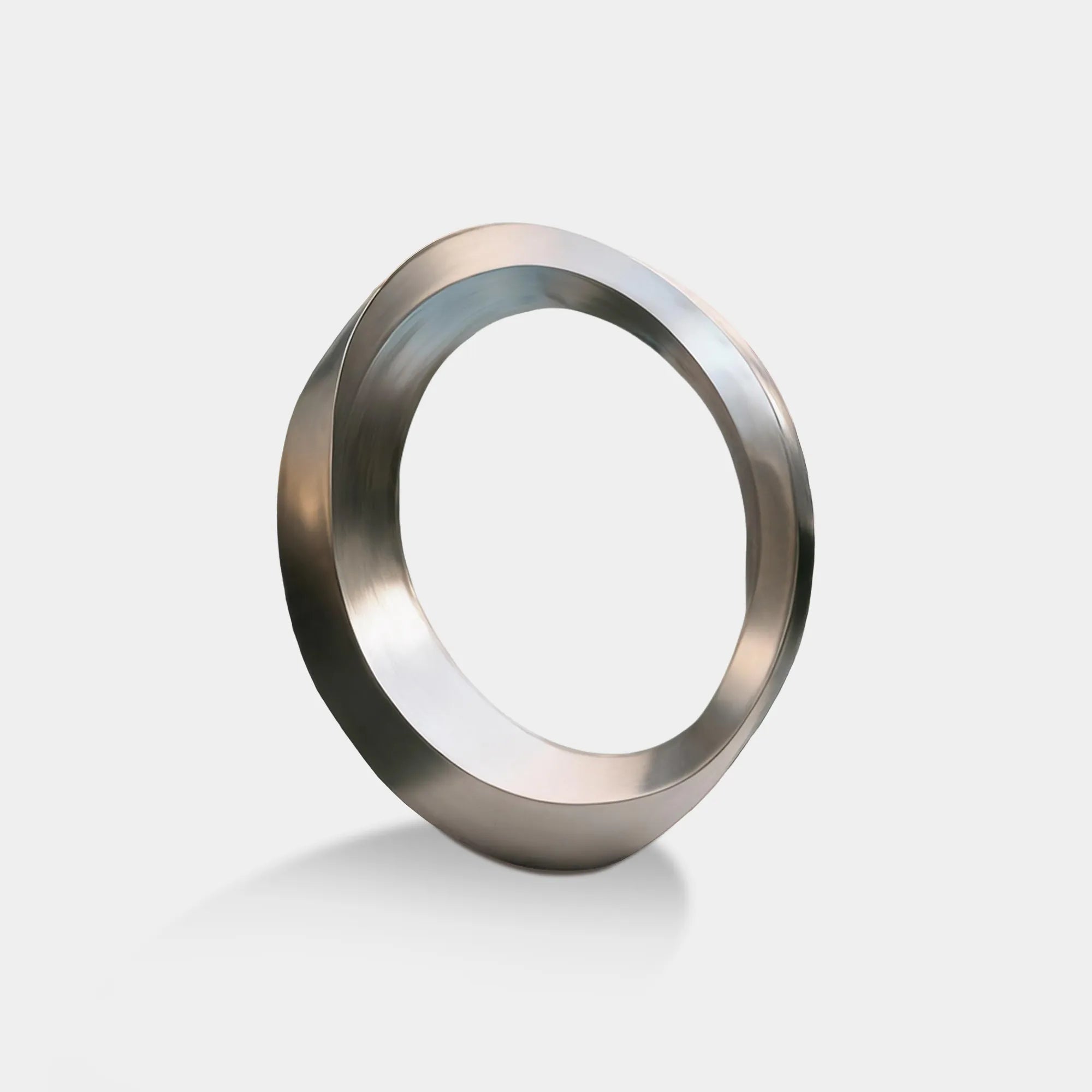 Brushed stainless steel circular ring sculpture in front of swimming pool and modern villa.