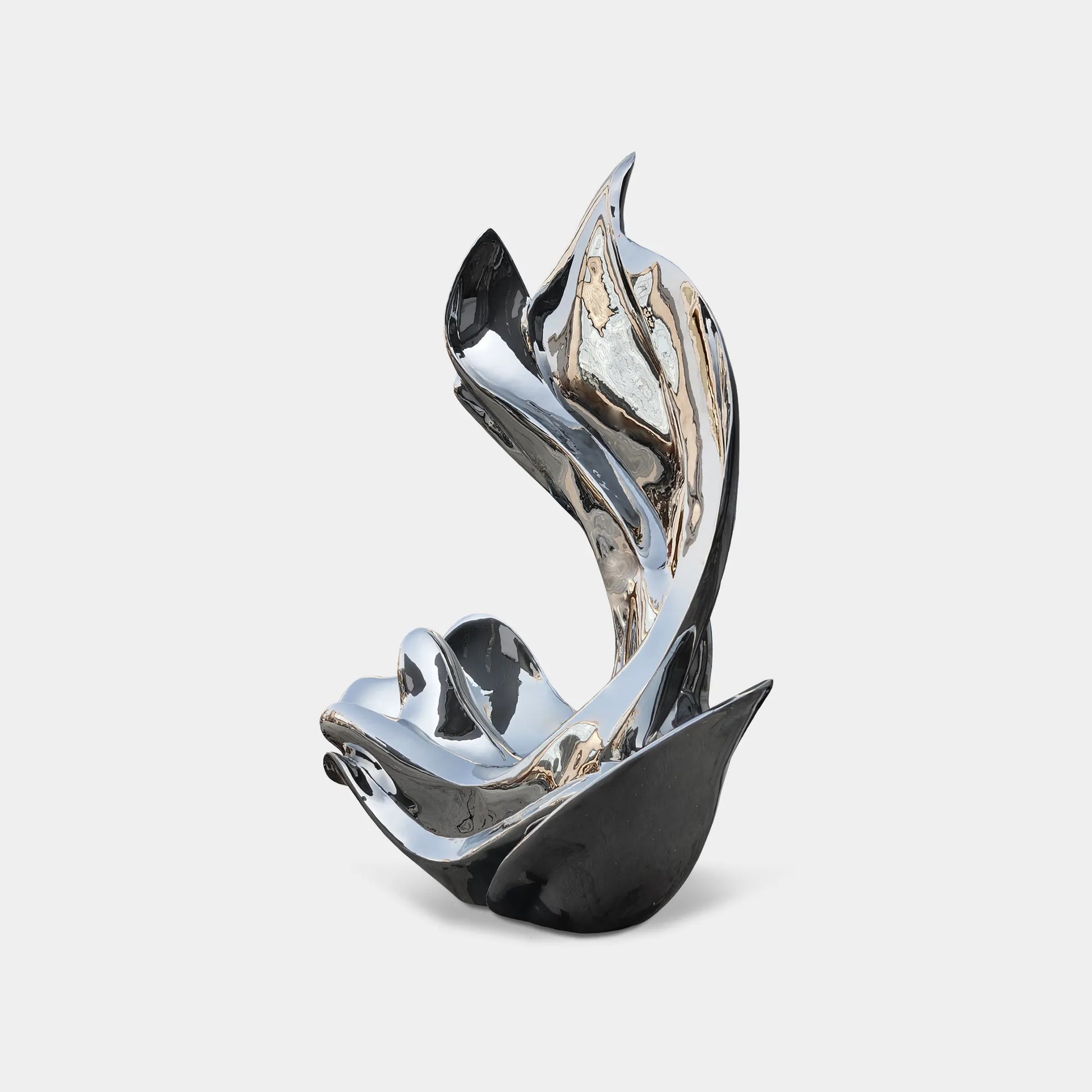Mirror polished stainless steel abstract sculpture with fluid curved form beside pool with glass building. 