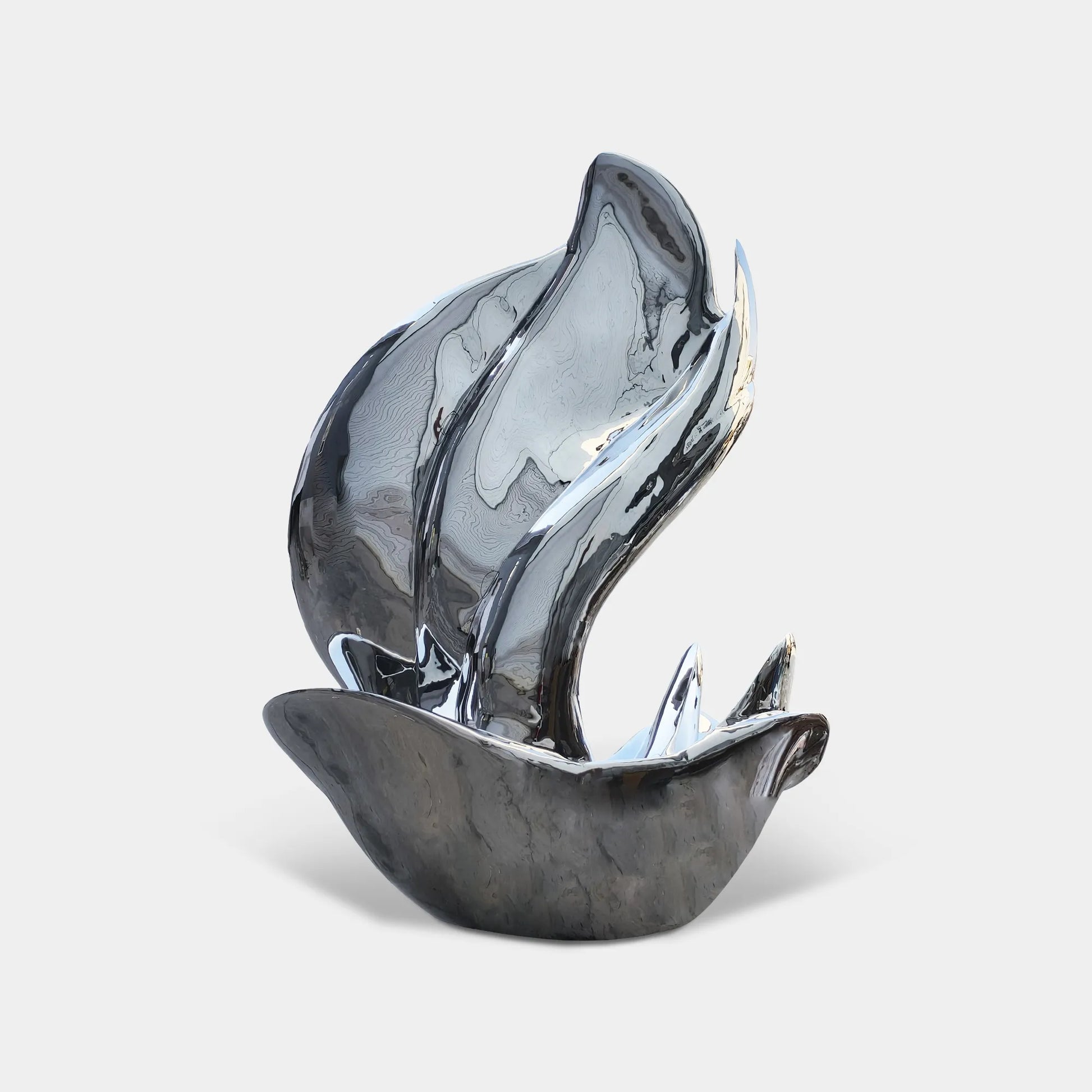 Mirror polished stainless steel abstract sculpture with fluid curved form beside pool with glass building. 