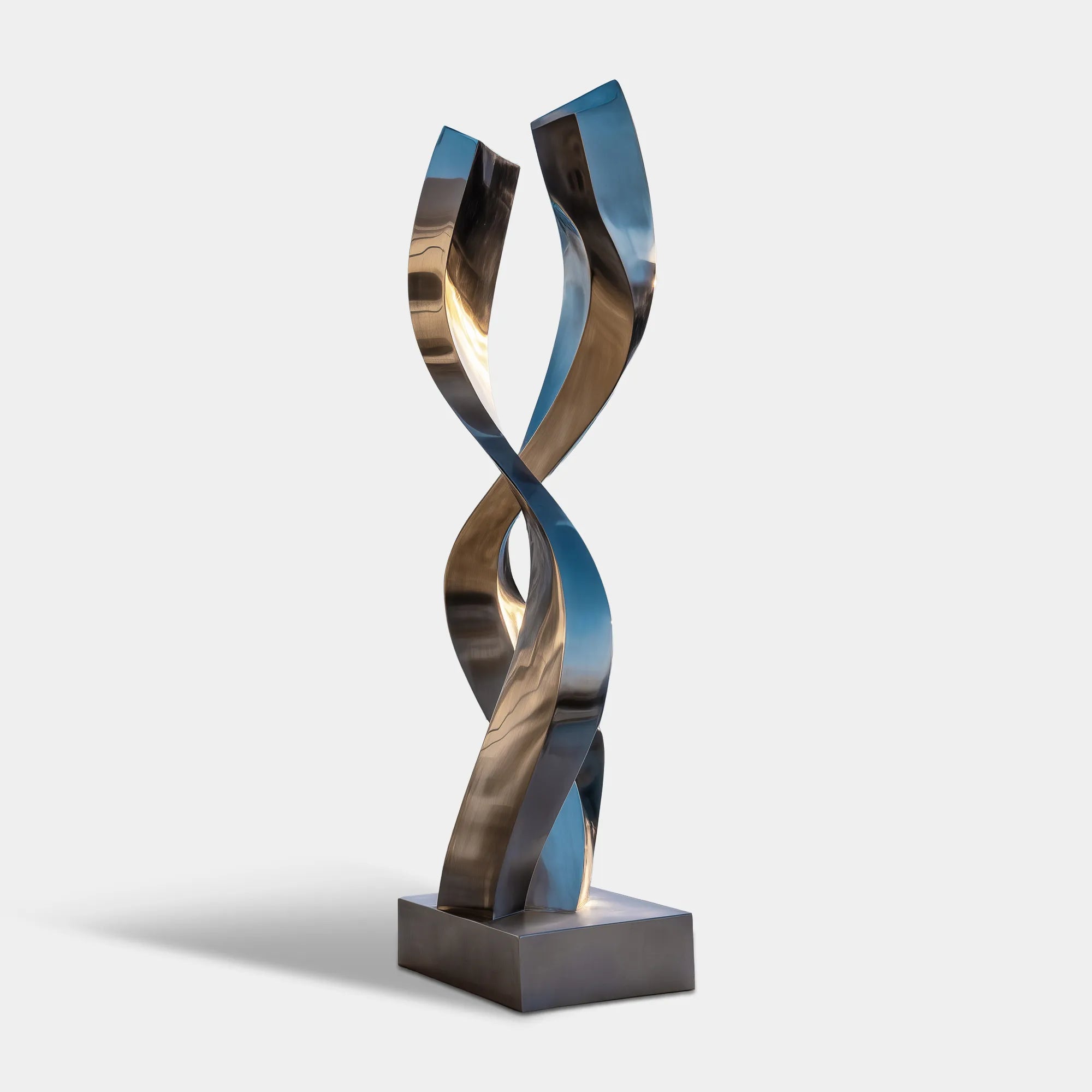 Tall mirror polished stainless steel spiral sculpture beside an infinity pool in a coastal villa terrace overlooking the ocean.
