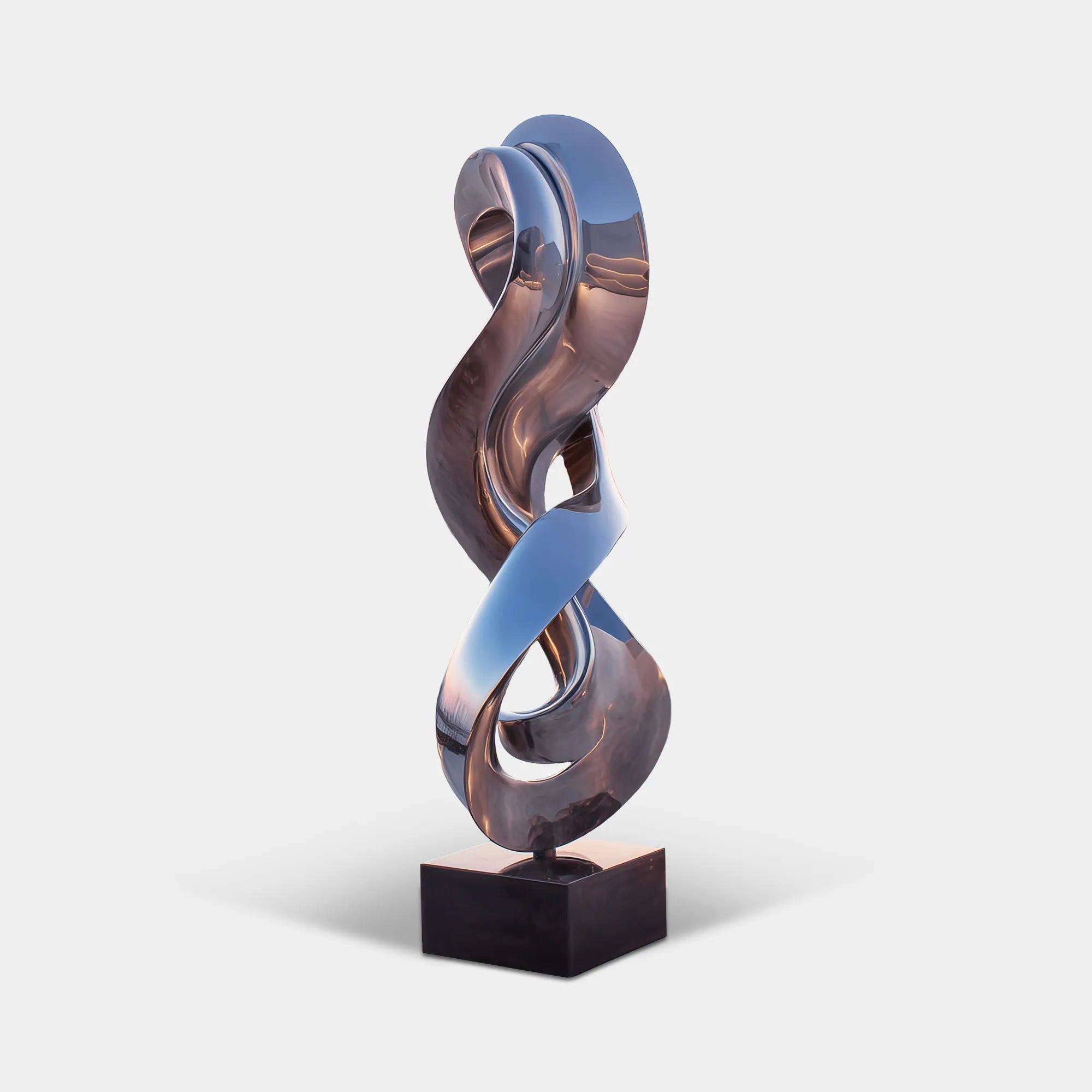 Mirror twisted curve stainless steel sculpture stands on tiled rooftop terrace overlooking coastal white town.
