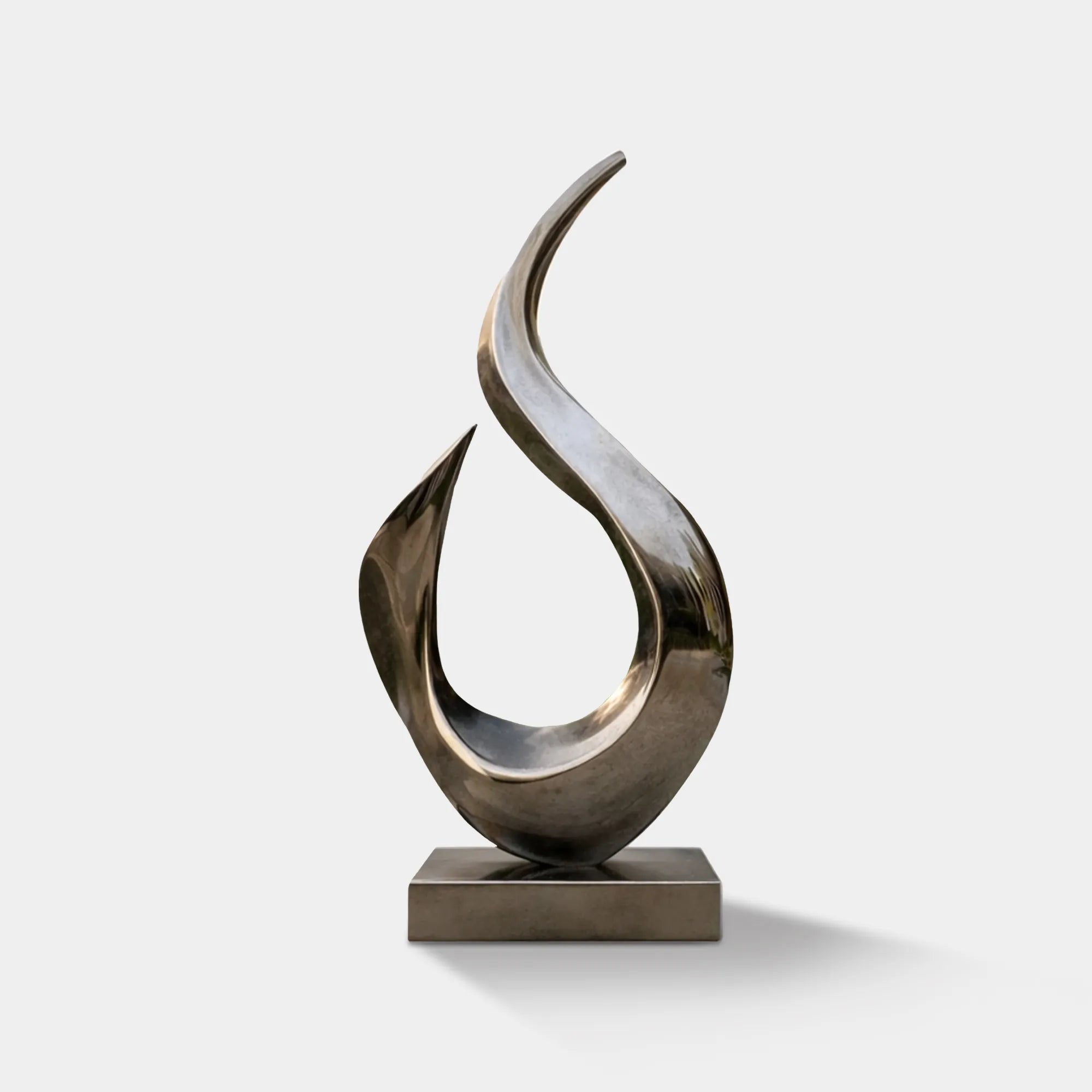 Mirror-polished stainless steel flowing form sculpture on a square base in a modern villa courtyard.