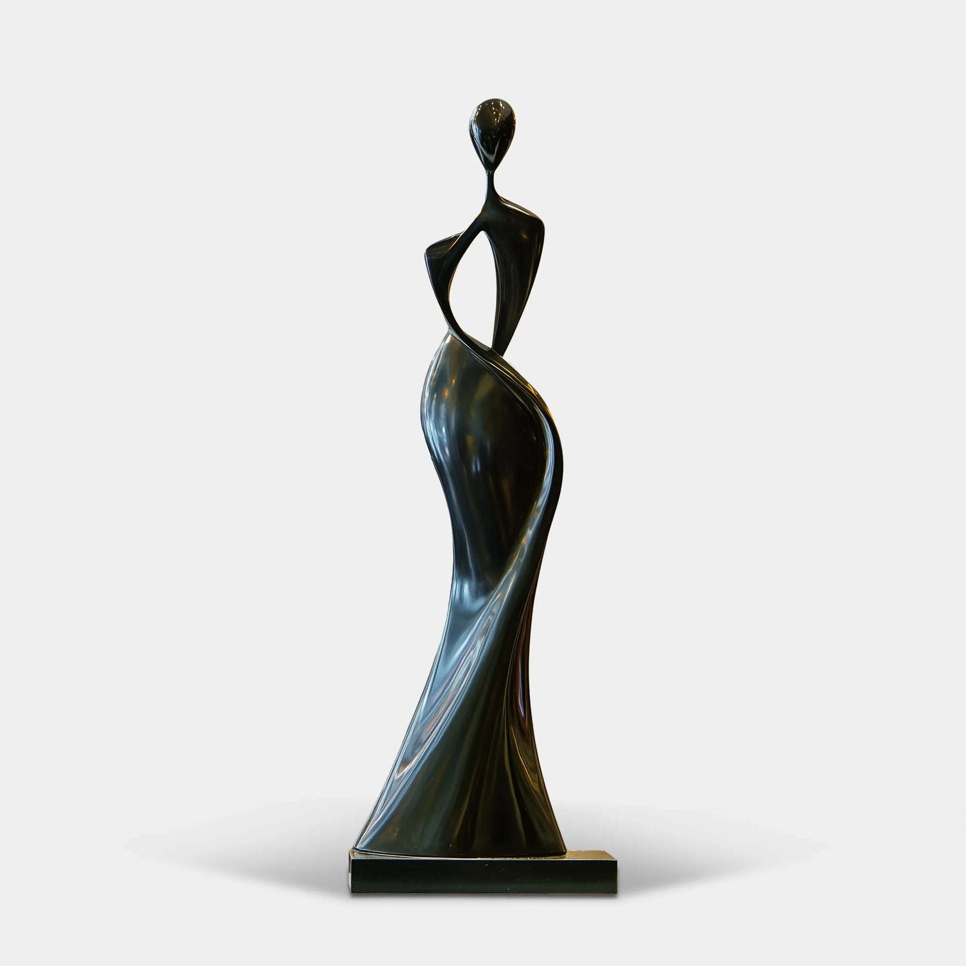 Black stainless steel sculpture in abstract twisting female design displays inside a lit residential entry hall.